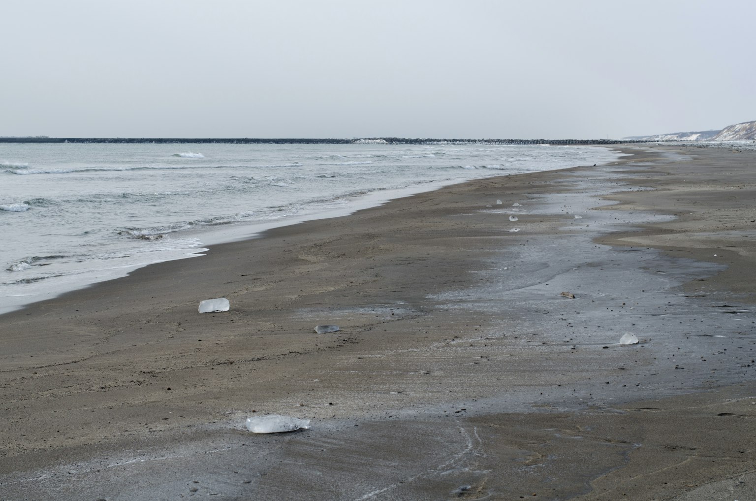 Escena de playa invernal mostrando la orilla de arena y las olas