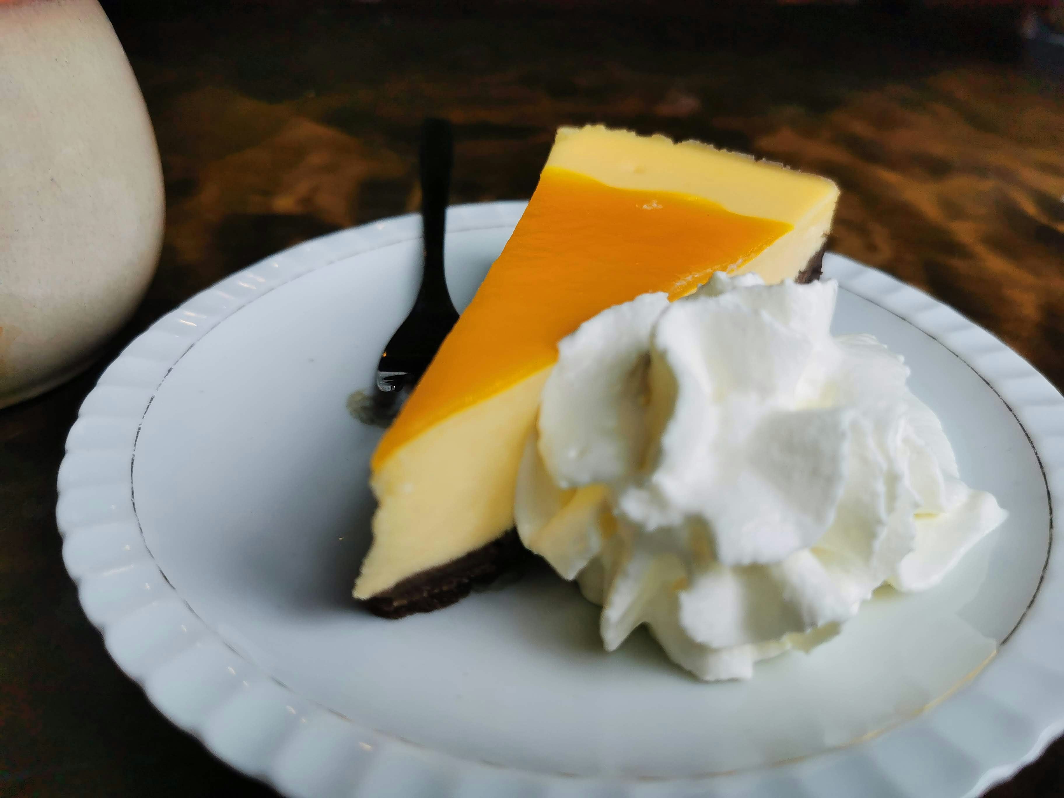 sepotong cheesecake dengan krim kocok di atas piring