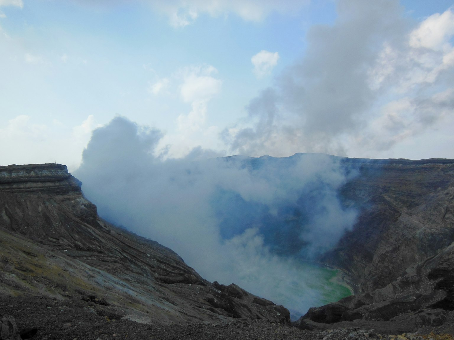 View of a volcanic crater with clouds of smoke