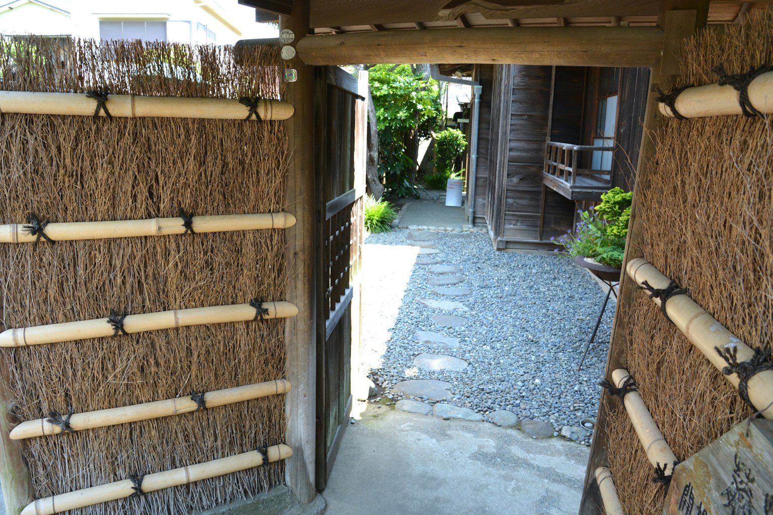 Vista a través de una puerta japonesa tradicional con vegetación y un camino de piedra