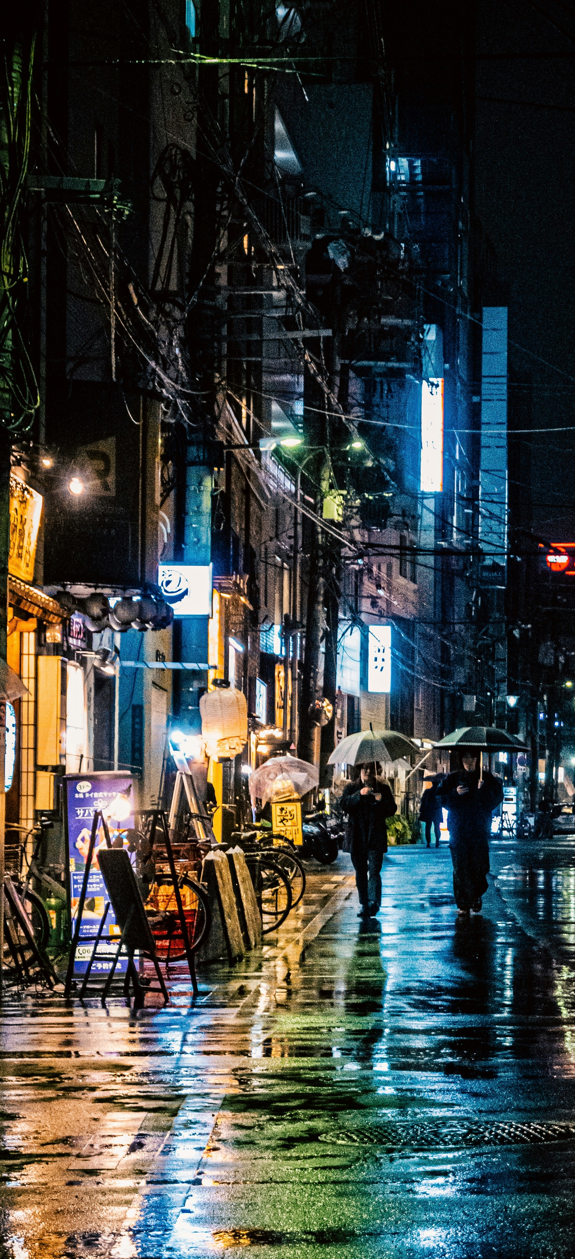 雨上がりの路地に並ぶ自転車と看板の夜景