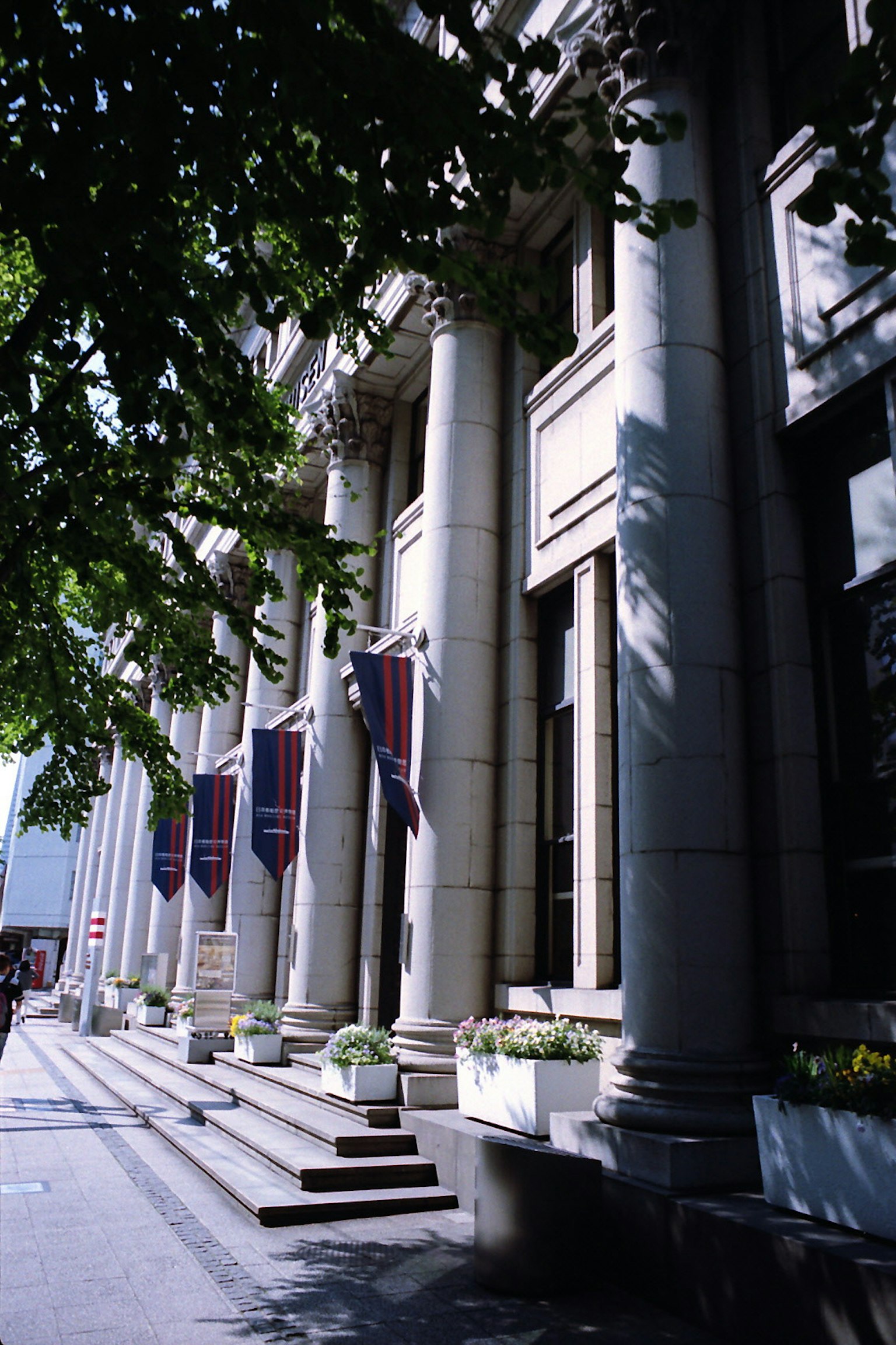 Vue de rue d'un bâtiment avec des colonnes et des drapeaux