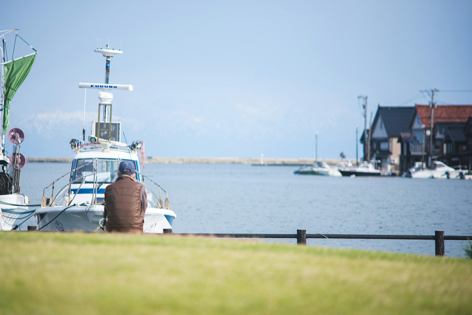 Person watching boats in a quiet harbor blue sea and sky in the background