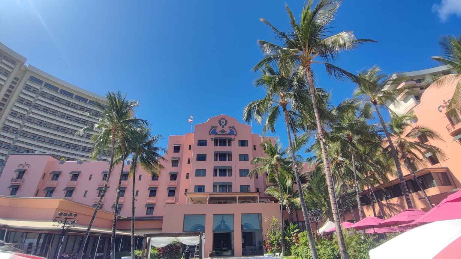 Un hotel rosa rodeado de palmeras bajo un cielo azul claro
