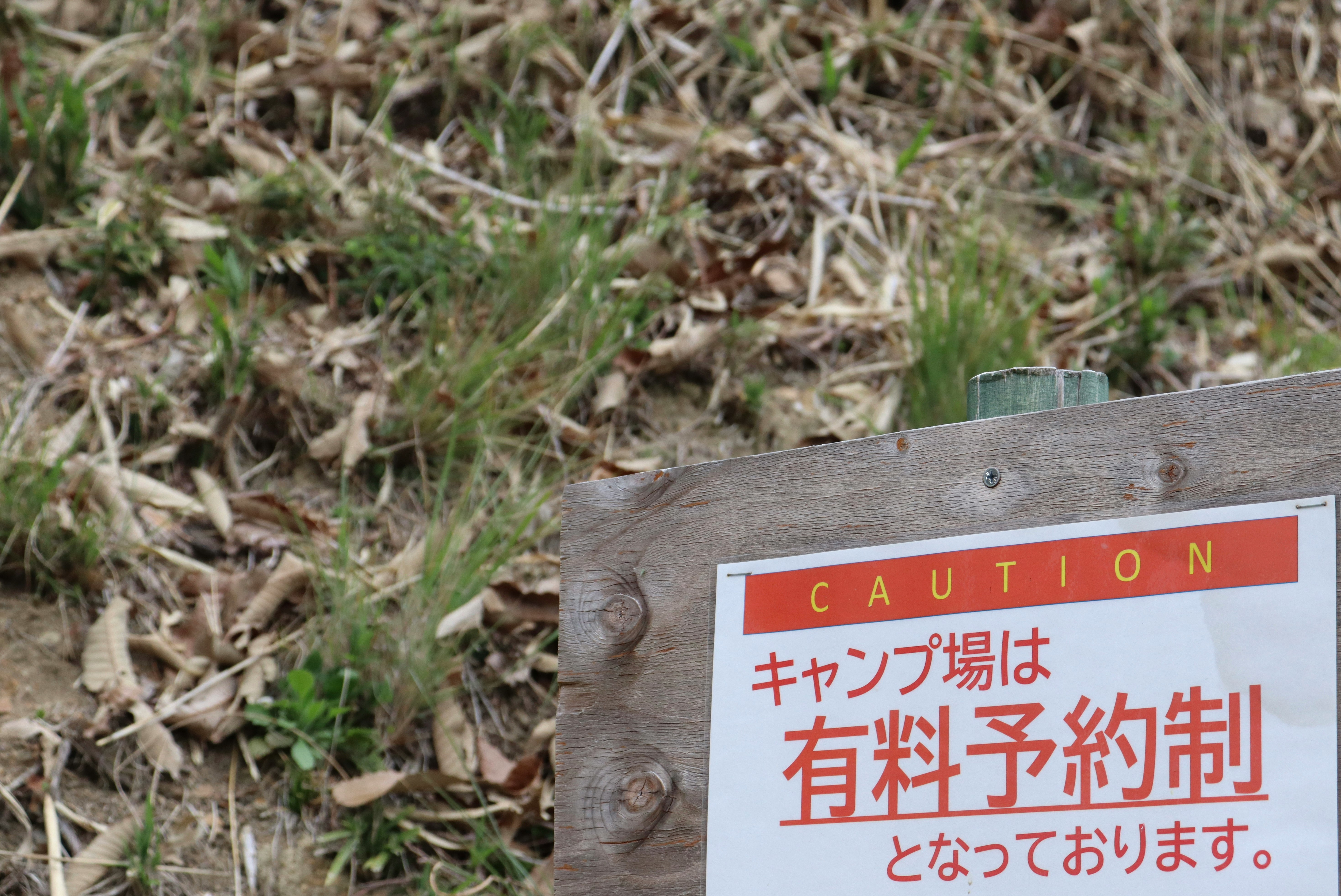 草むらの木製看板に書かれた有料予約制の案内
