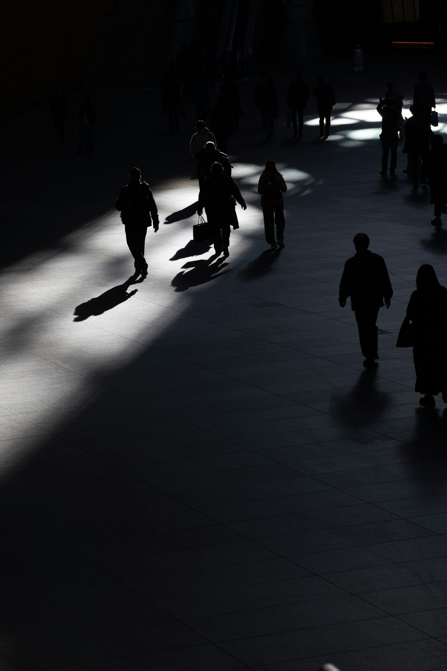 Siluetas de personas caminando en sombras con rayos de luz