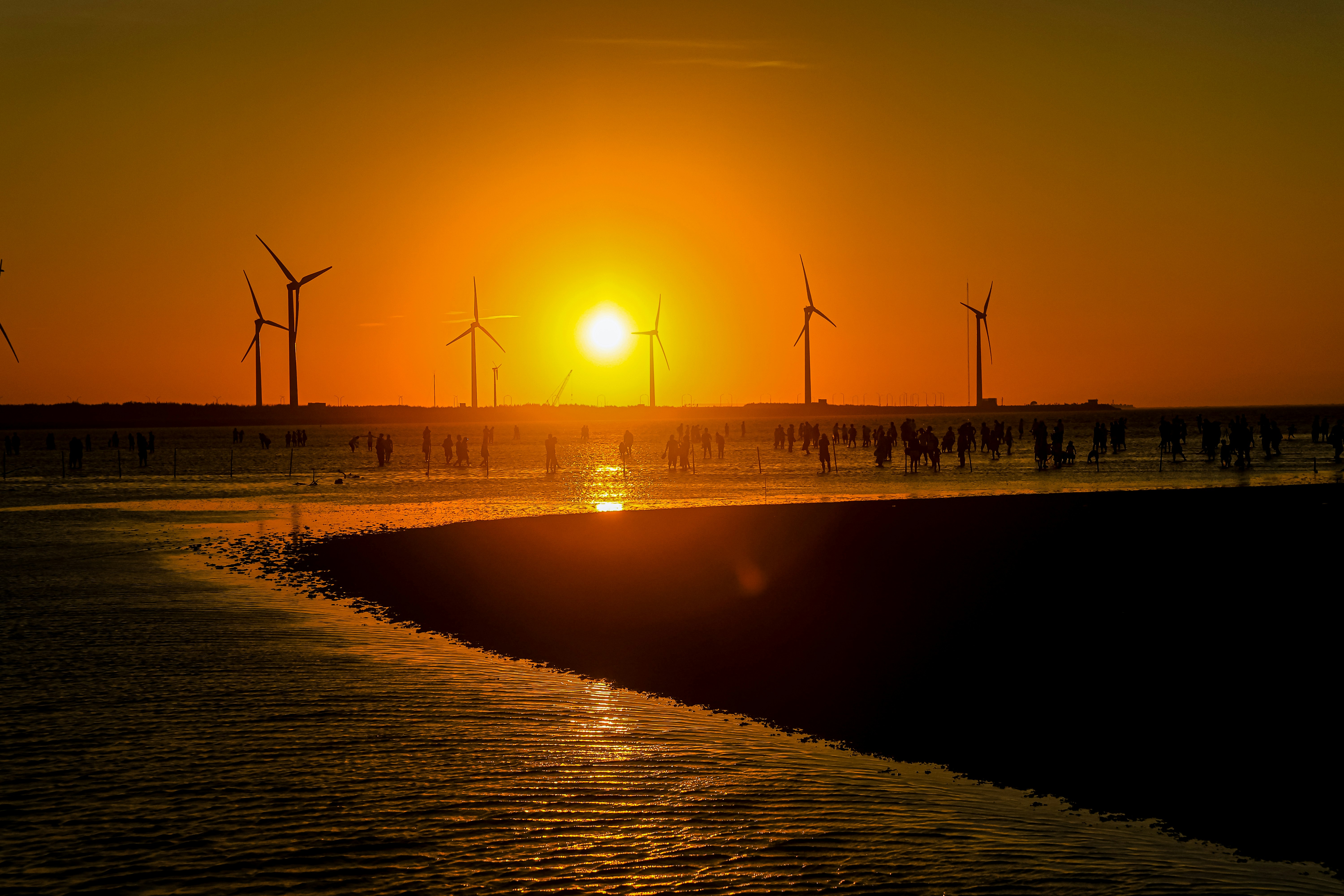 海岬の夕陽と風車が並ぶ海岸の風景