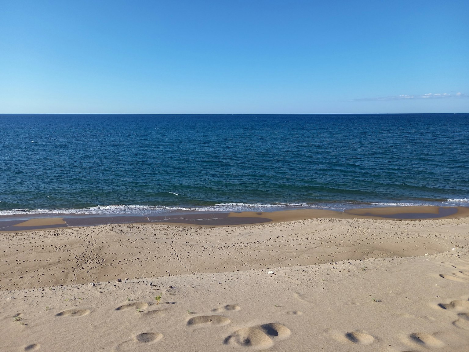 Pemandangan pantai tenang dengan laut biru dan tepi pasir