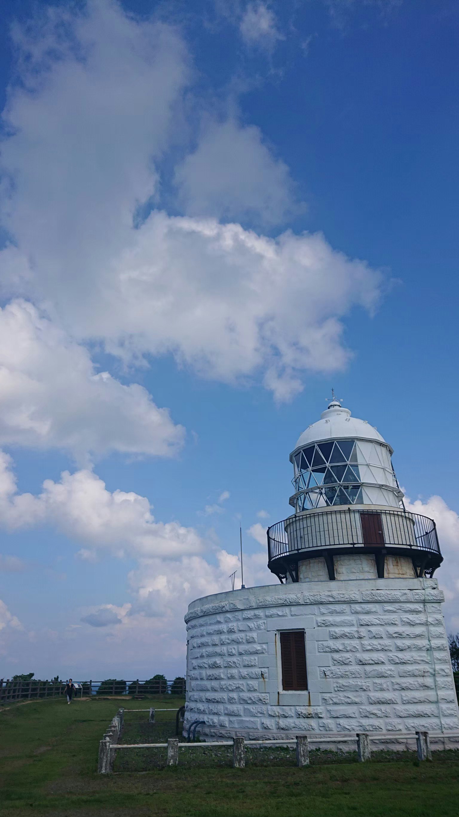 Weißes Leuchtturmgebäude unter einem blauen Himmel mit Wolken