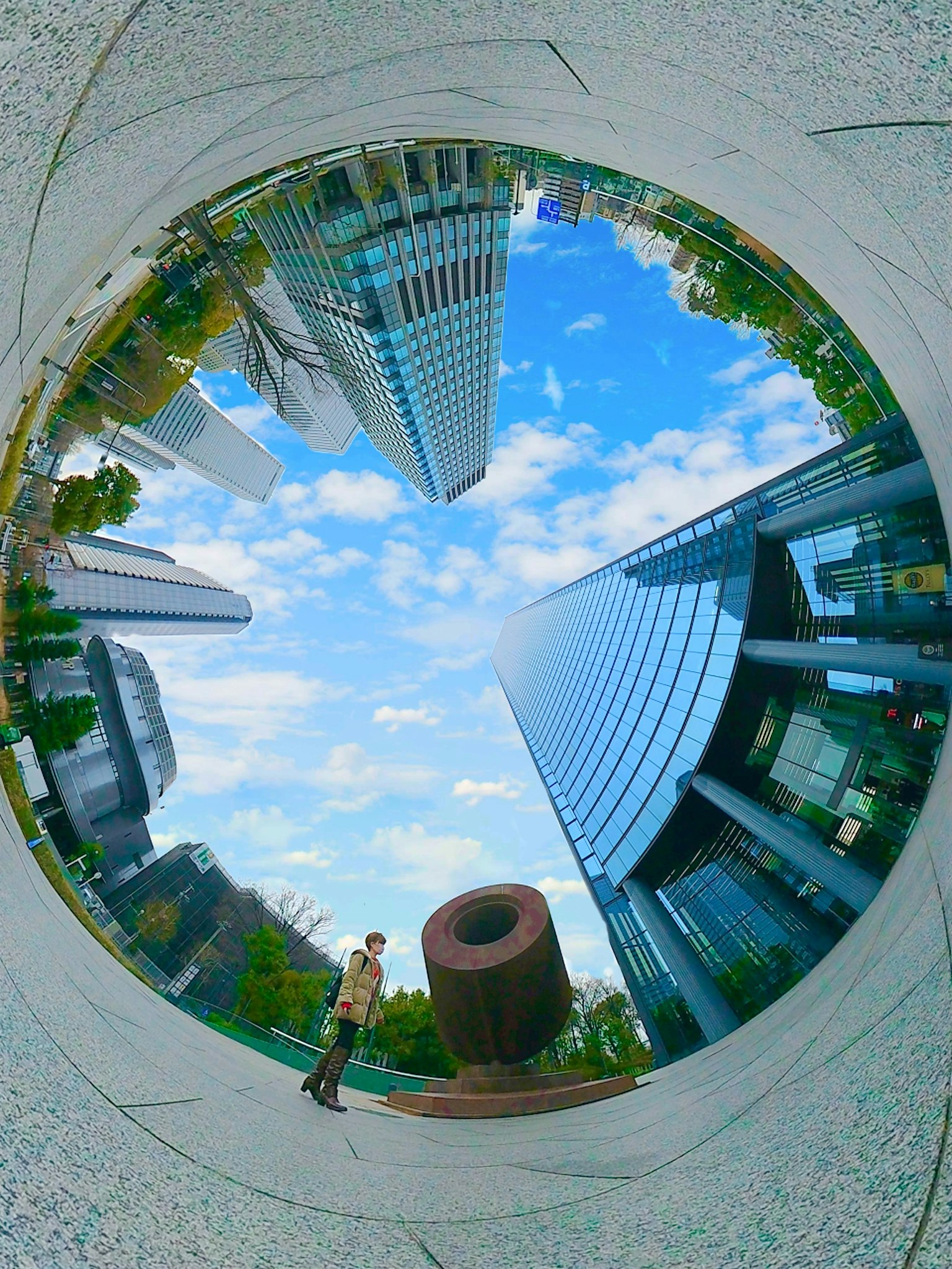 A person standing in a circular composition with skyscrapers and blue sky
