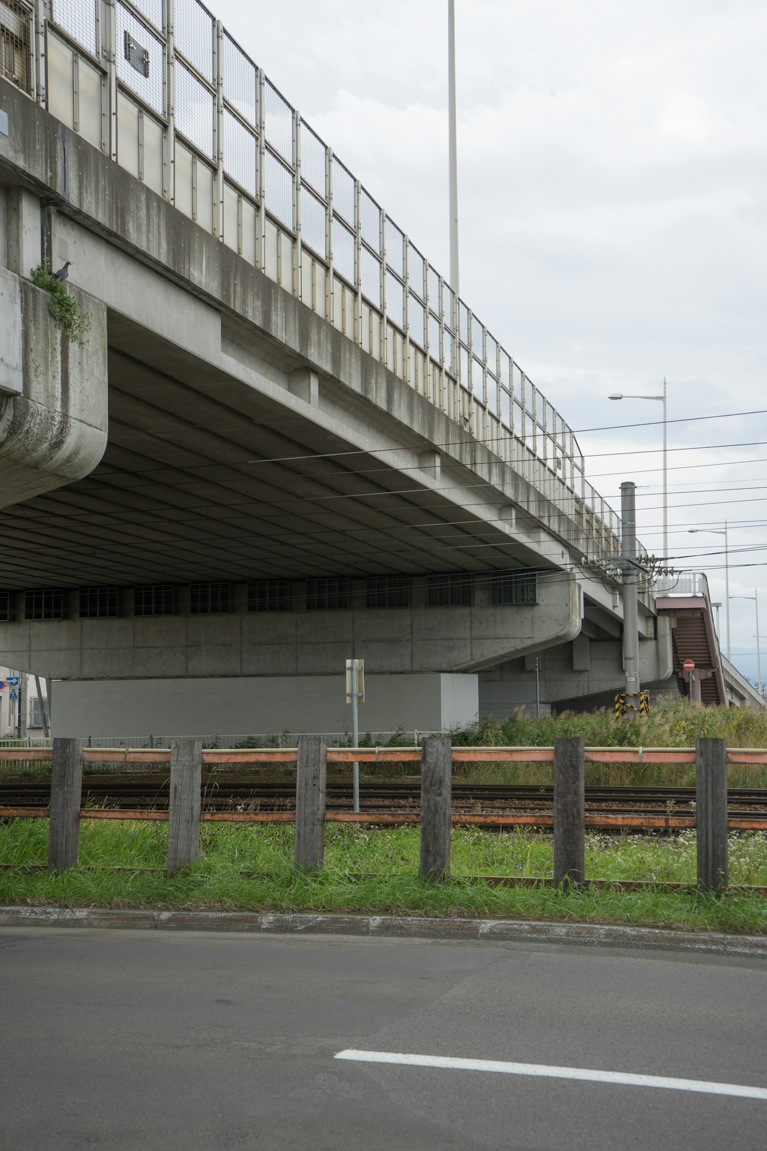 Blick auf eine Bahn- und Straßenkreuzung unter einer erhöhten Brücke