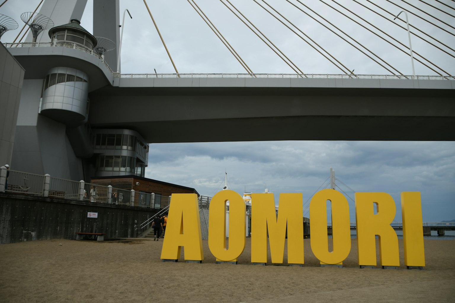 大型黃色標誌AOMORI，背景是橋