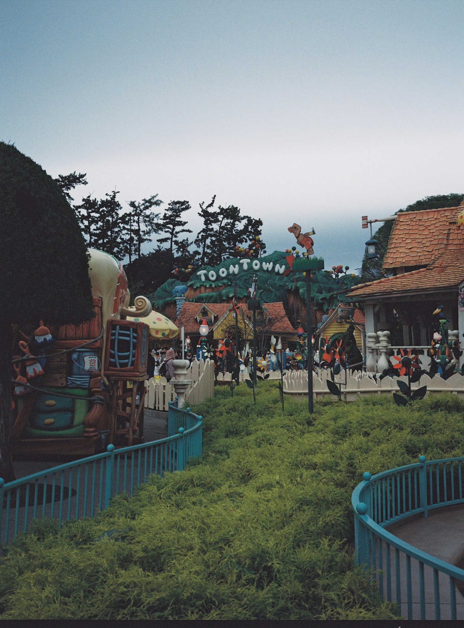 View of a theme park with the entrance to Toon Town visible people enjoying a green grassy area