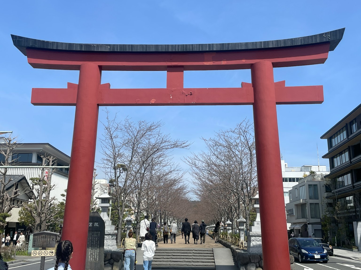 Puerta torii roja con personas caminando bajo un cielo azul