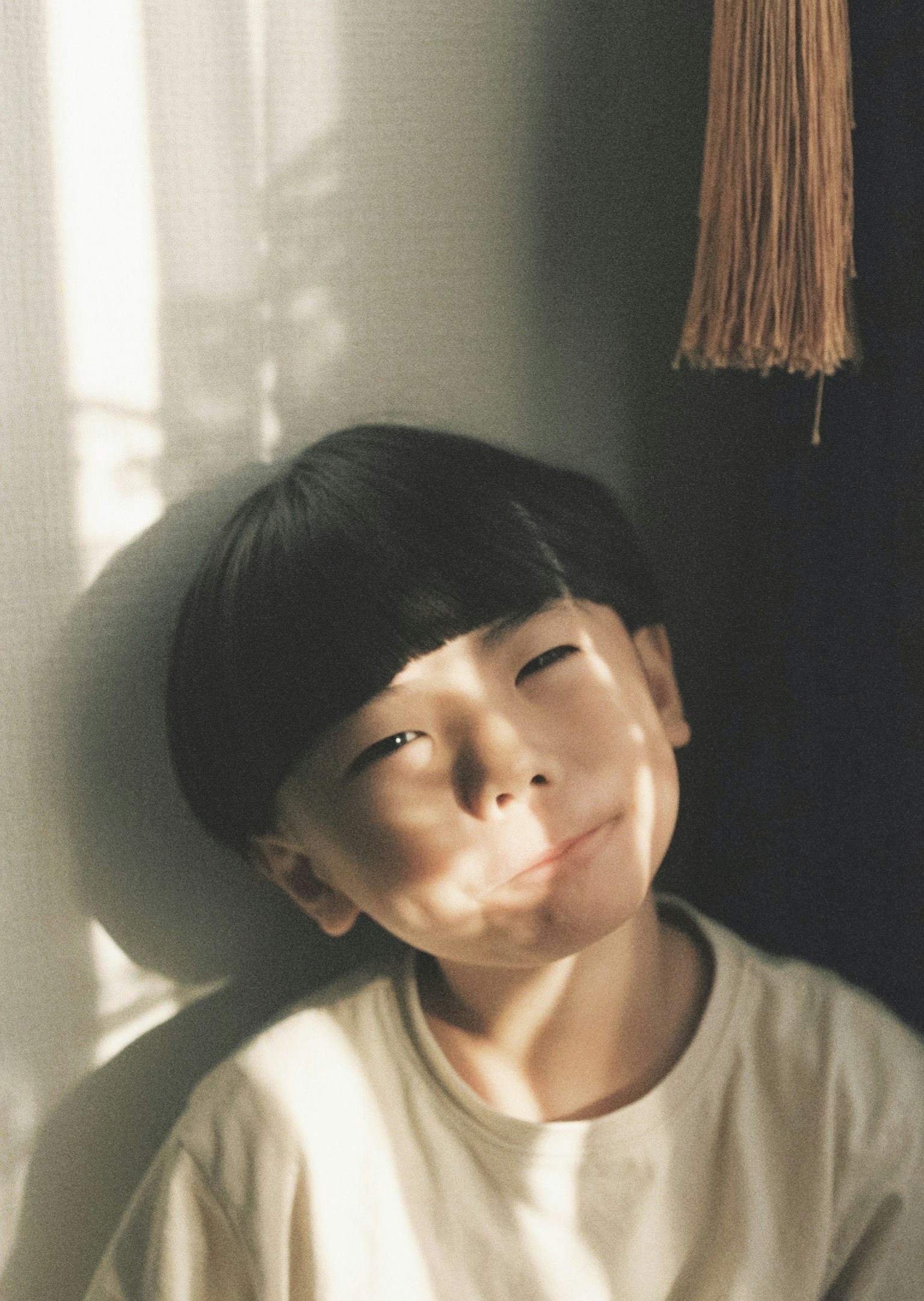 Smiling child's face illuminated by sunlight soft shadows and warm tones