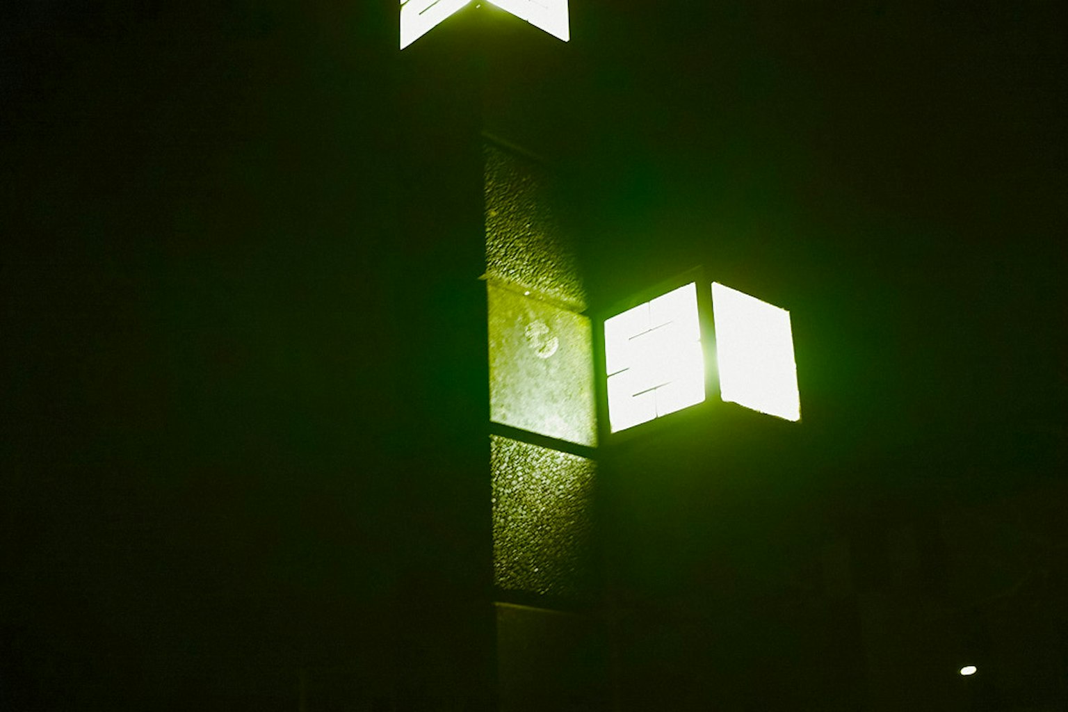 Struktur tinggi dengan lampu hijau persegi di latar belakang gelap