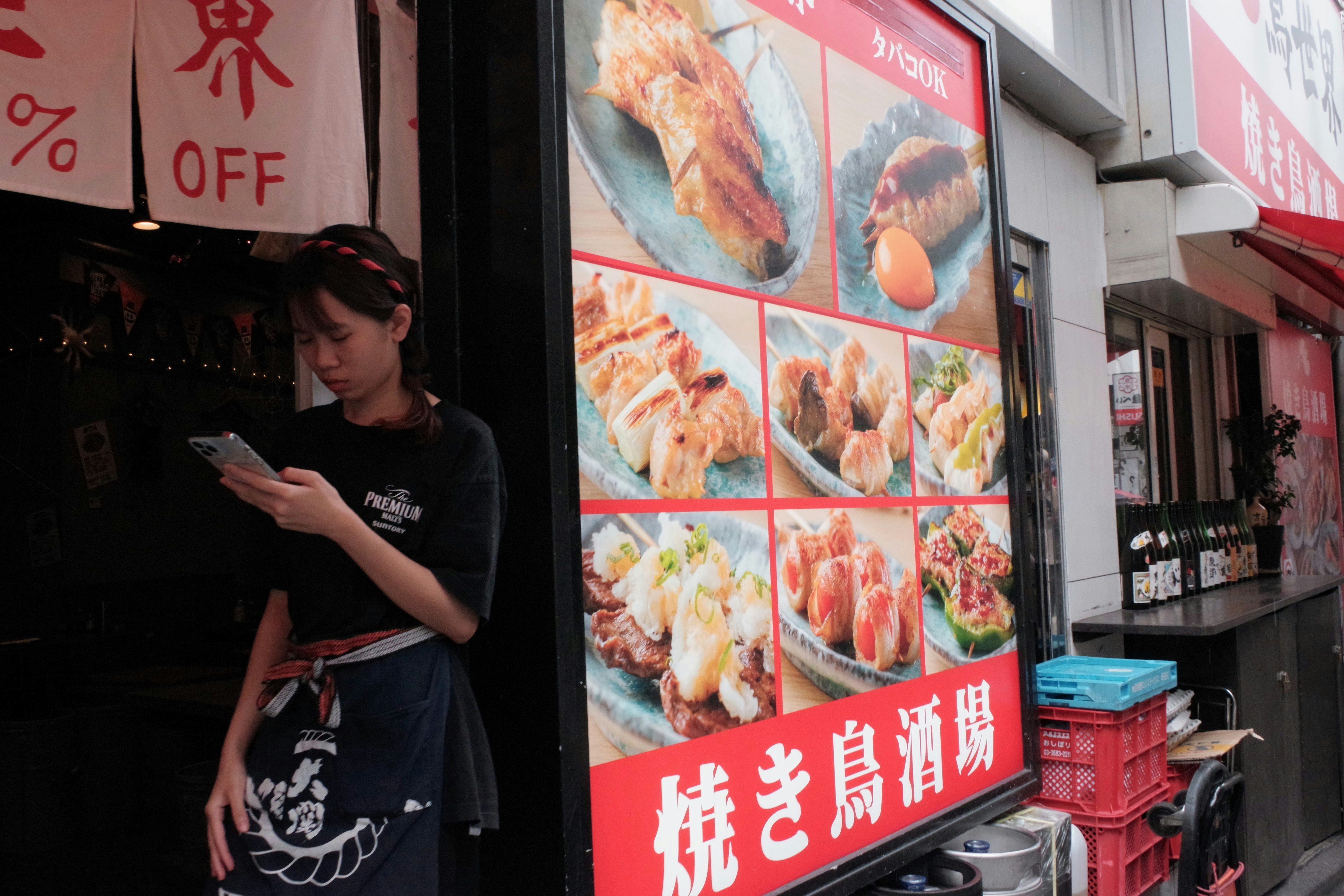 A person looking at a smartphone outside a street shop with fried food signs image
