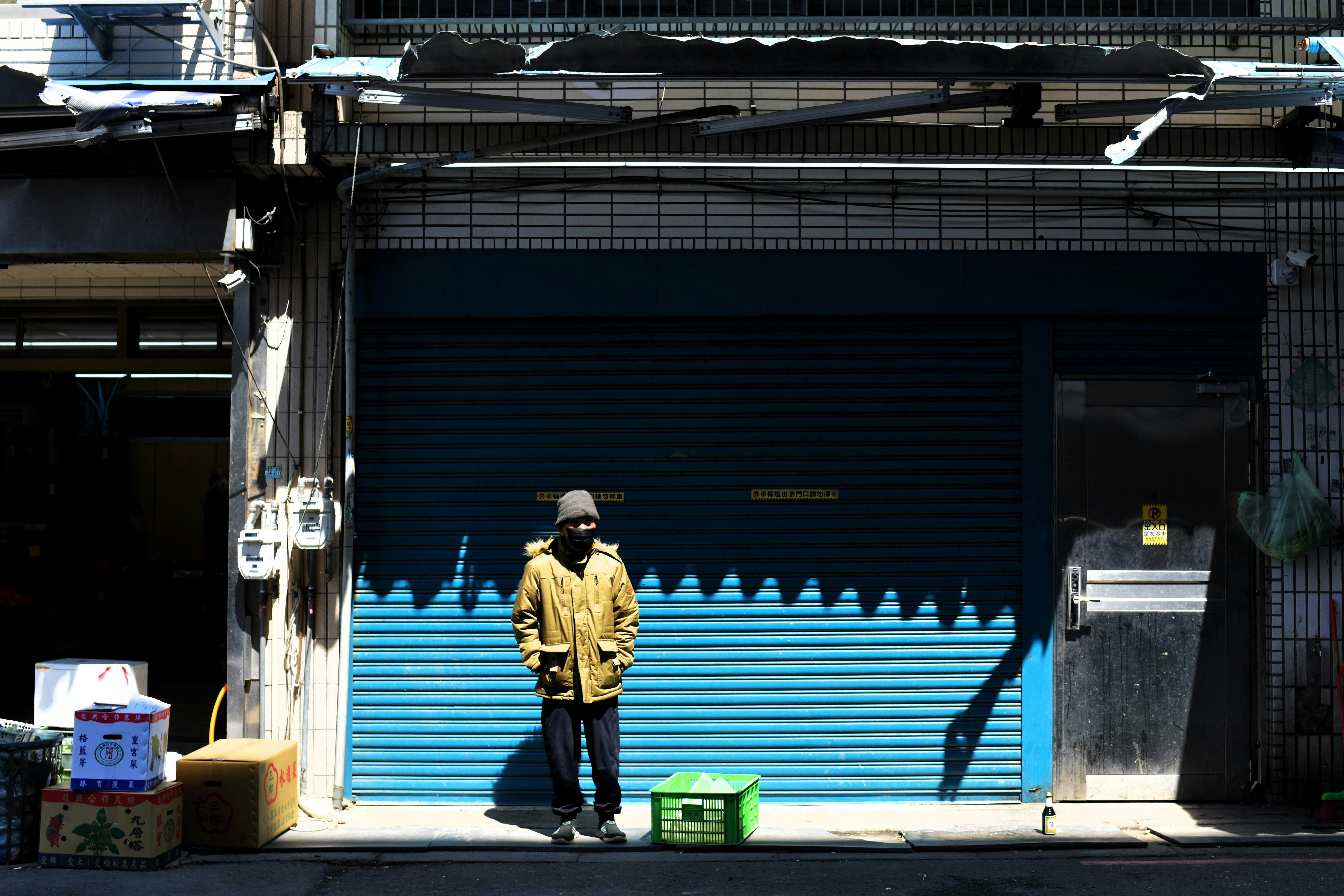 青いシャッターの前に立つ人物と街角の小物