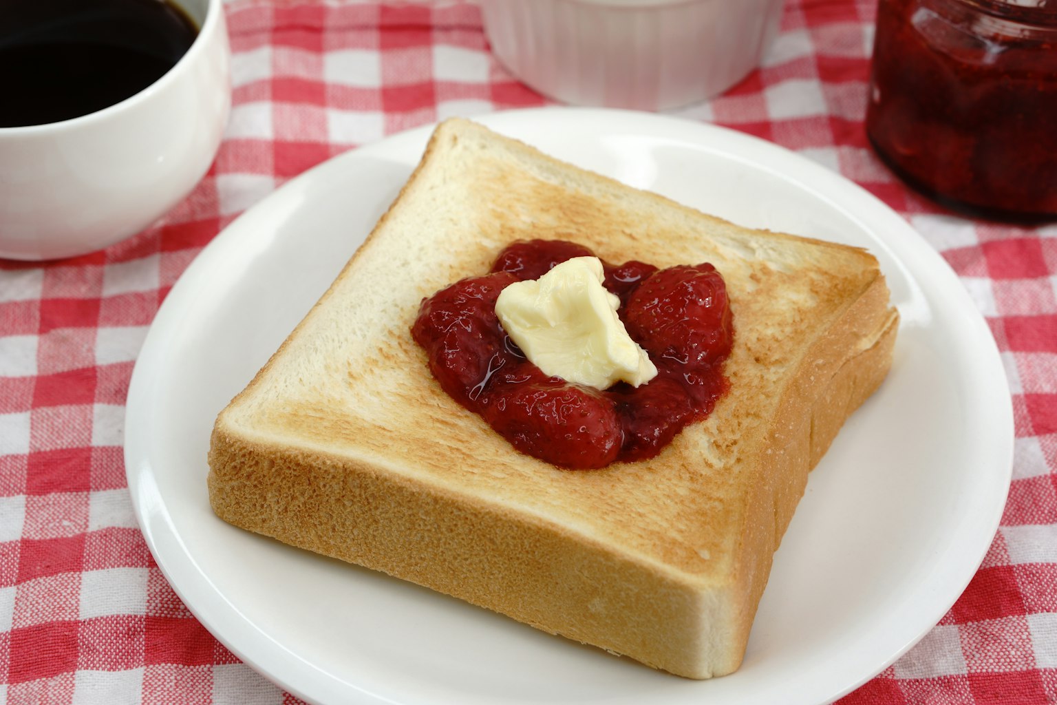 Tartine de pain grillé avec du beurre et de la confiture de fraises sur une assiette