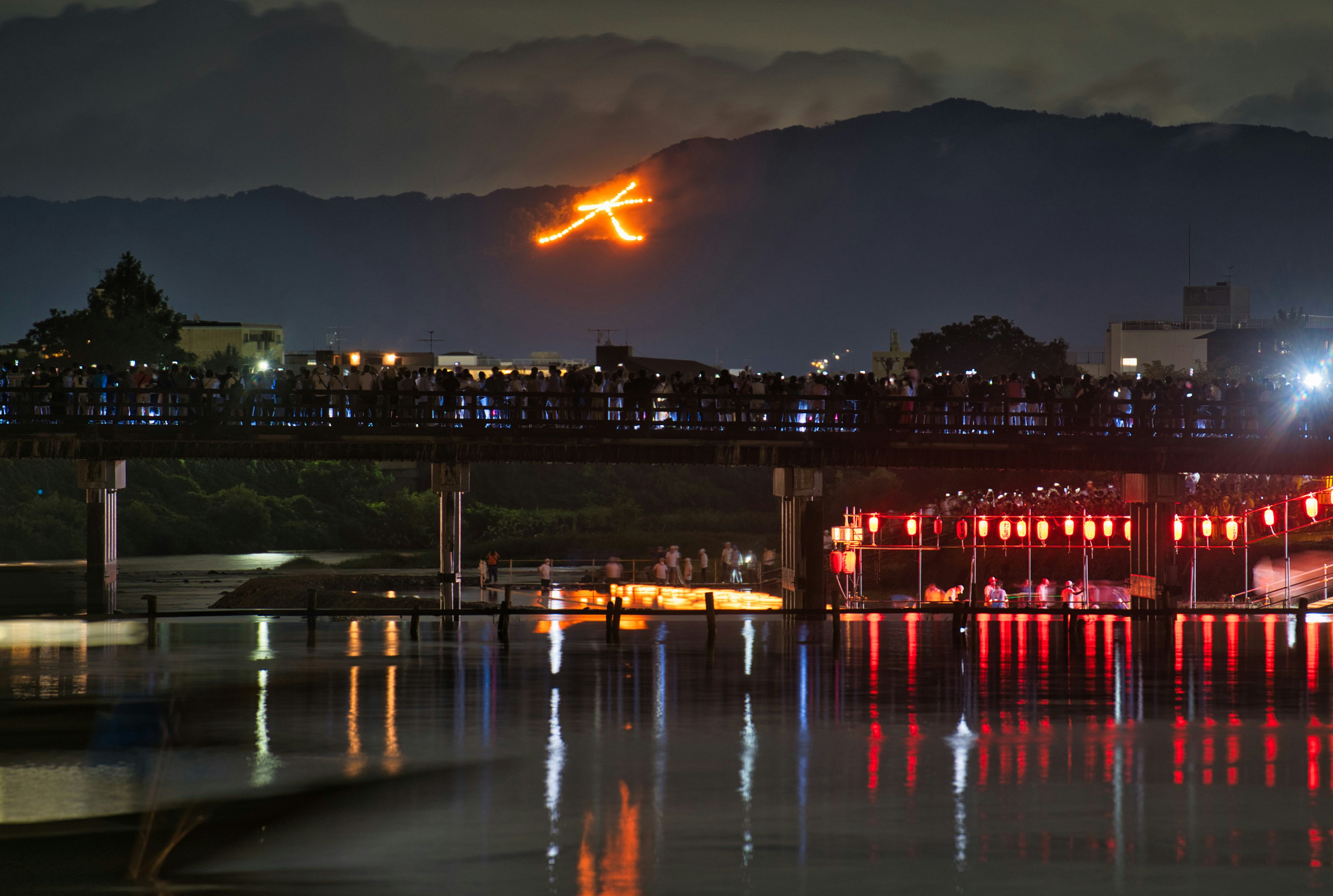 嵐山の渡月橋周辺で灯籠流しと送り火が見える夜景