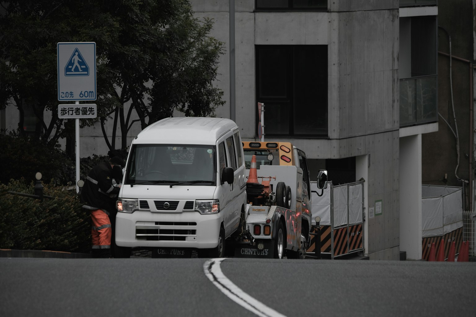 Un furgone bianco parcheggiato su una strada stretta con un camion dietro in un paesaggio urbano