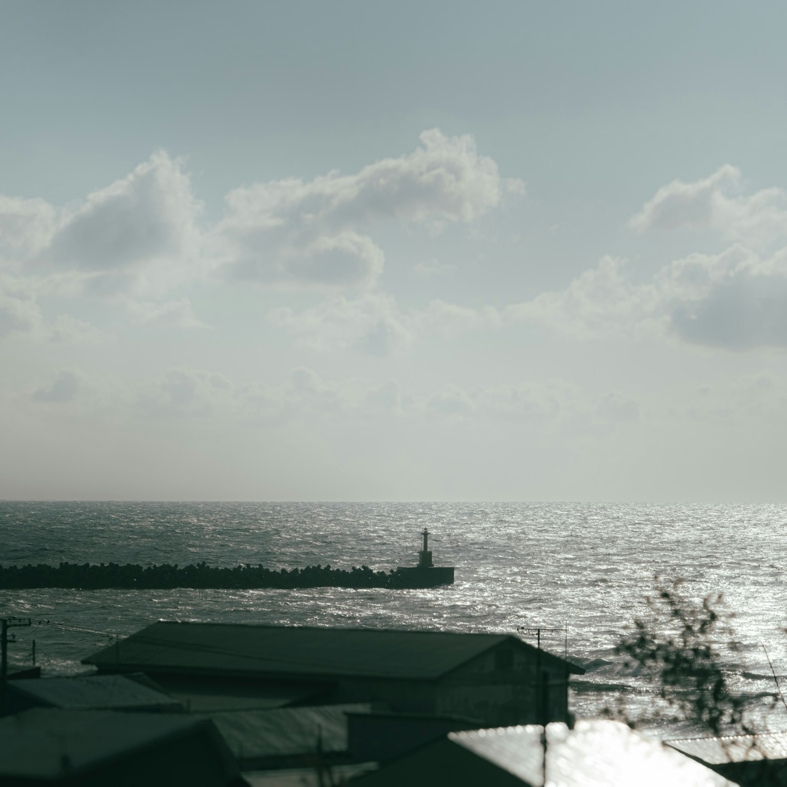 Paysage maritime avec un phare et un ciel nuageux des vagues scintillantes