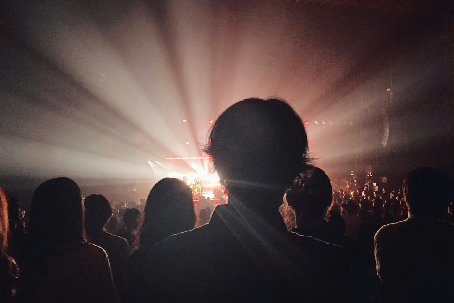 Public silhouetté lors d'un concert avec des rayons de lumière