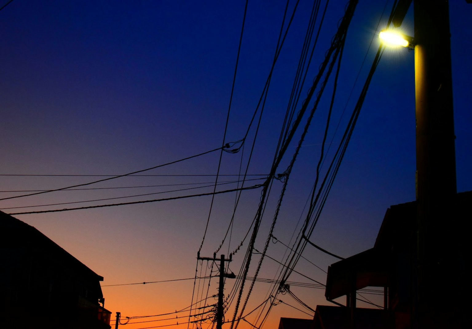 Silhouette de bâtiments et de lignes électriques au crépuscule