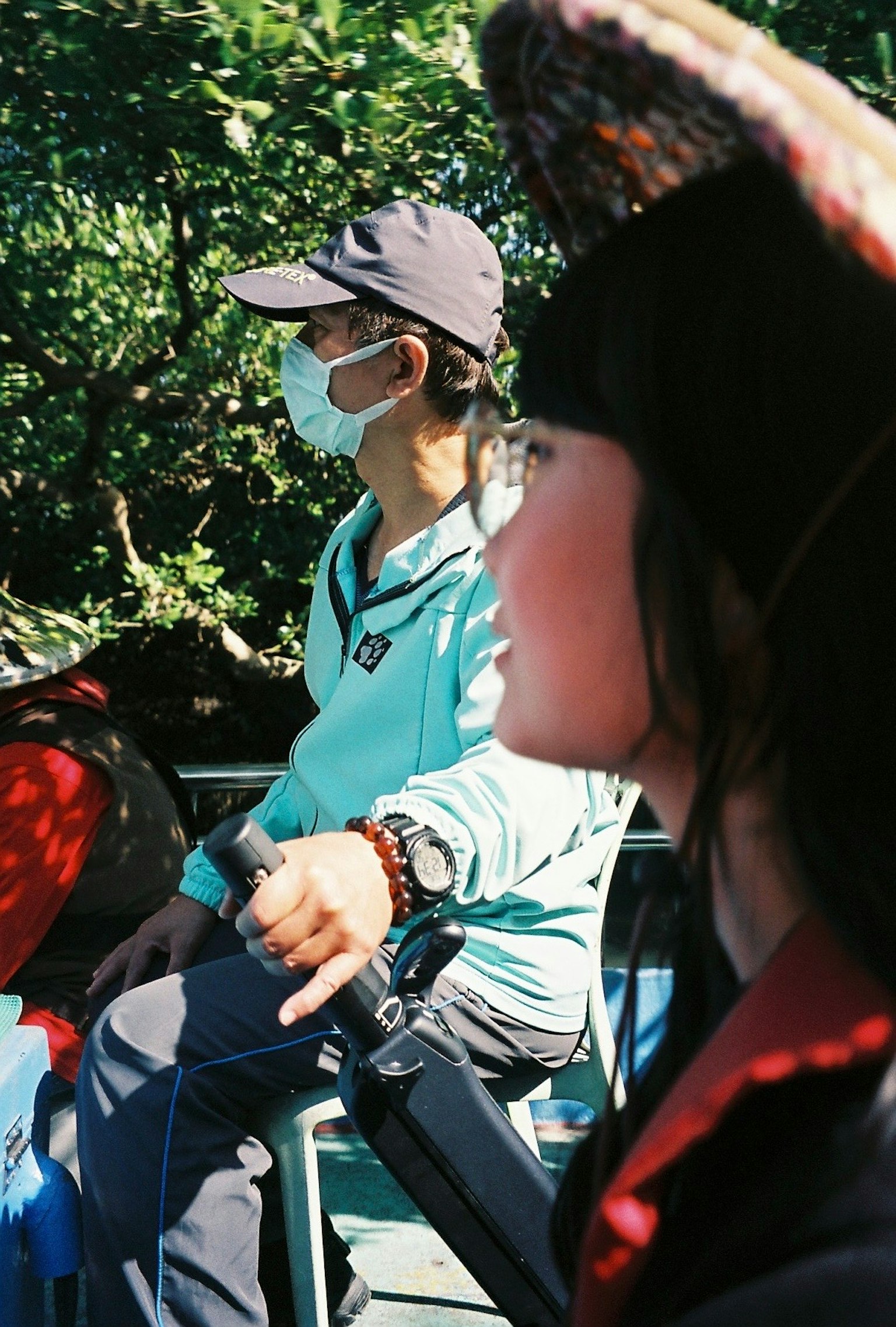 ชายในเสื้อสีน้ำเงินและหมวกนั่งอยู่ในเรือพร้อมกับผู้หญิงในพื้นหน้า