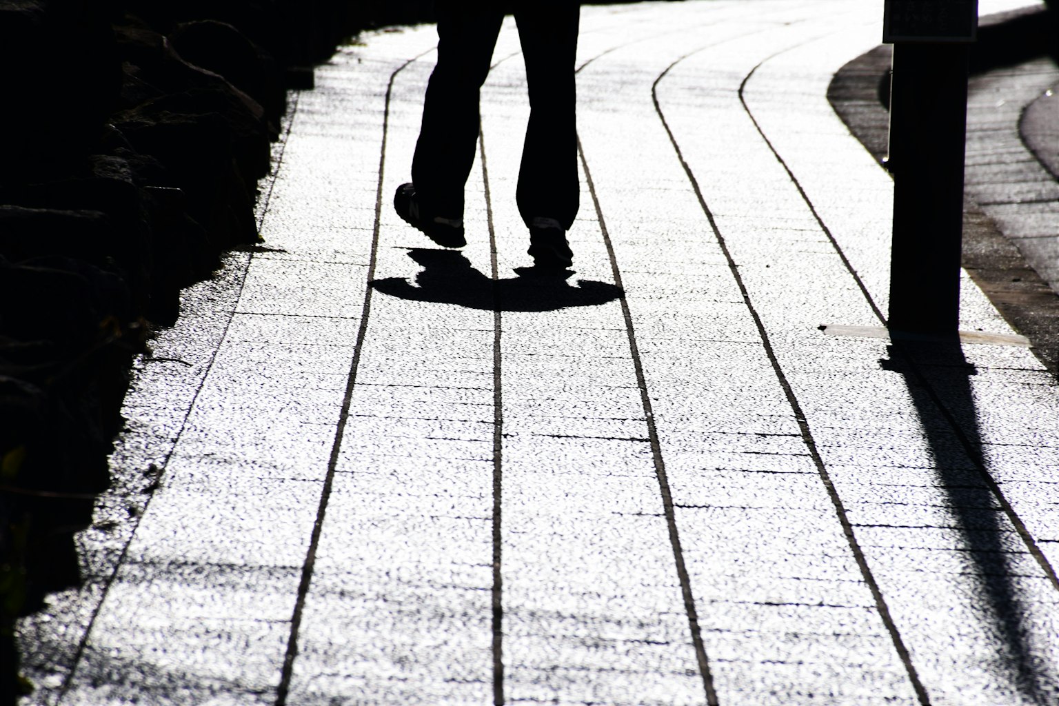 A person walking on a curved pathway with shadows