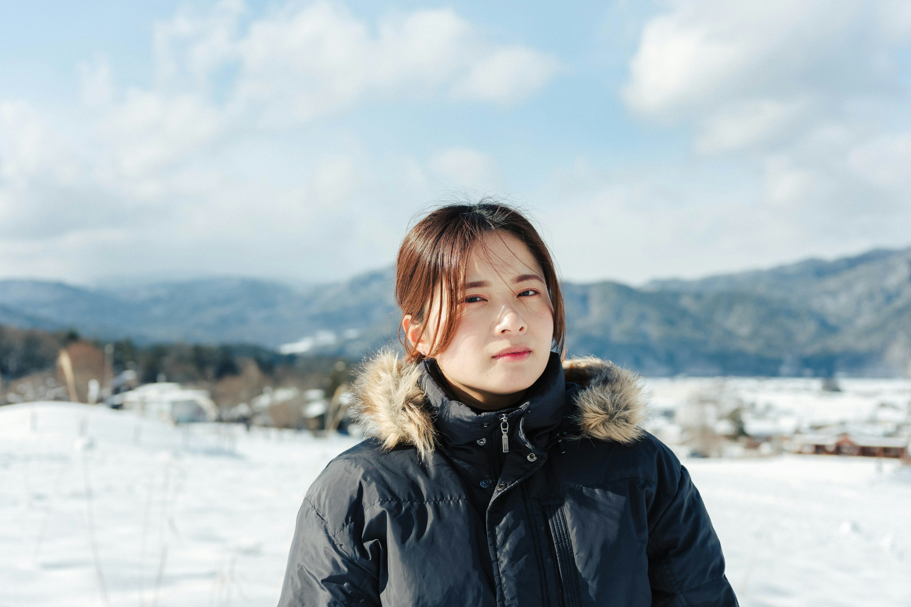 雪景色の中でファー付きコートを着た女性