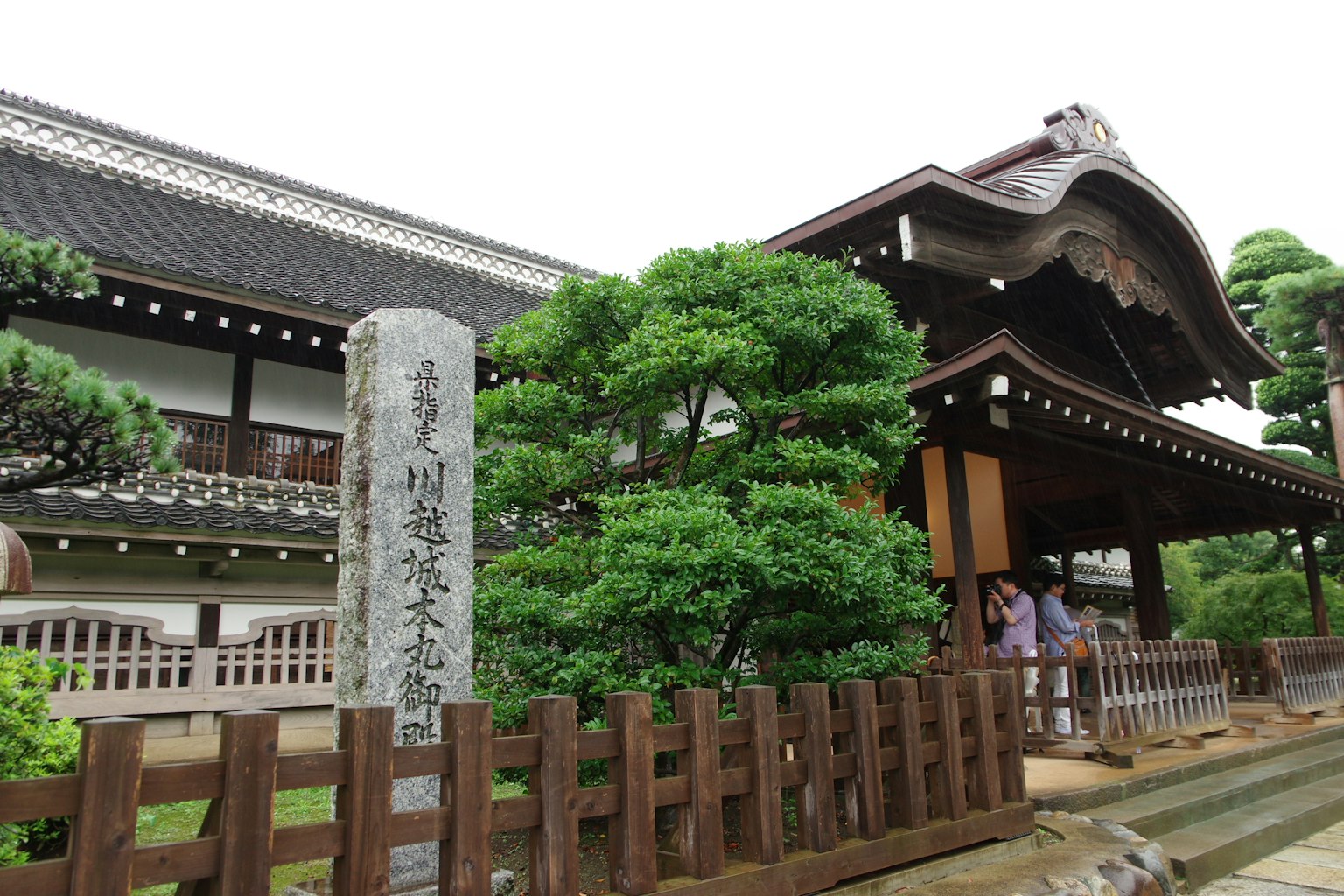 传统日本建筑与郁郁葱葱的绿树和石碑