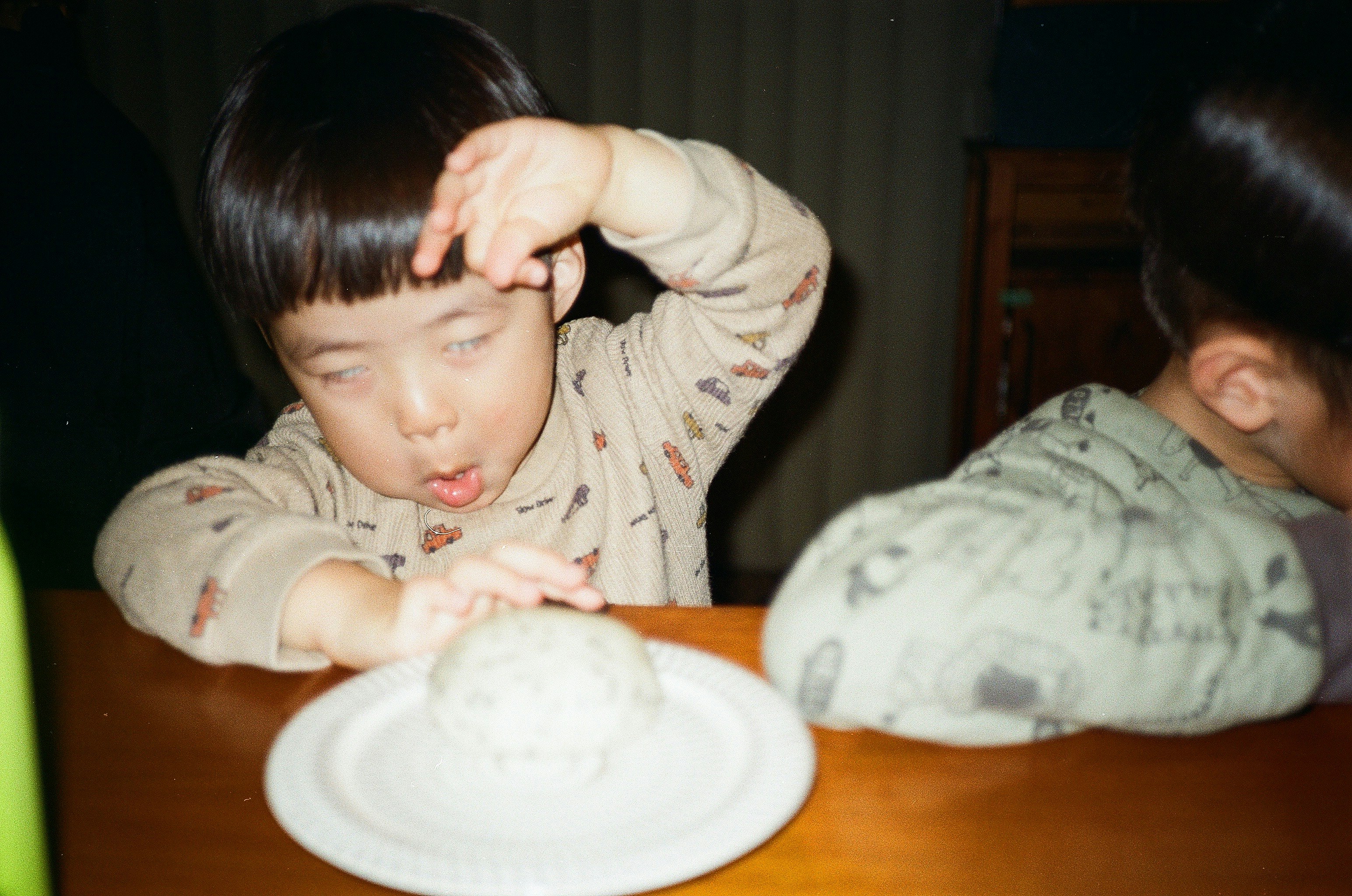 Enfants à table, un enfant touche sa tête