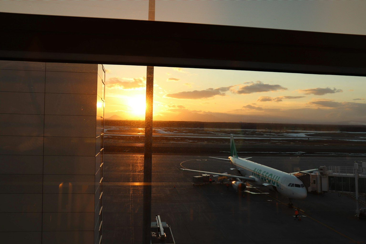 Sunset view from an airport window with an airplane