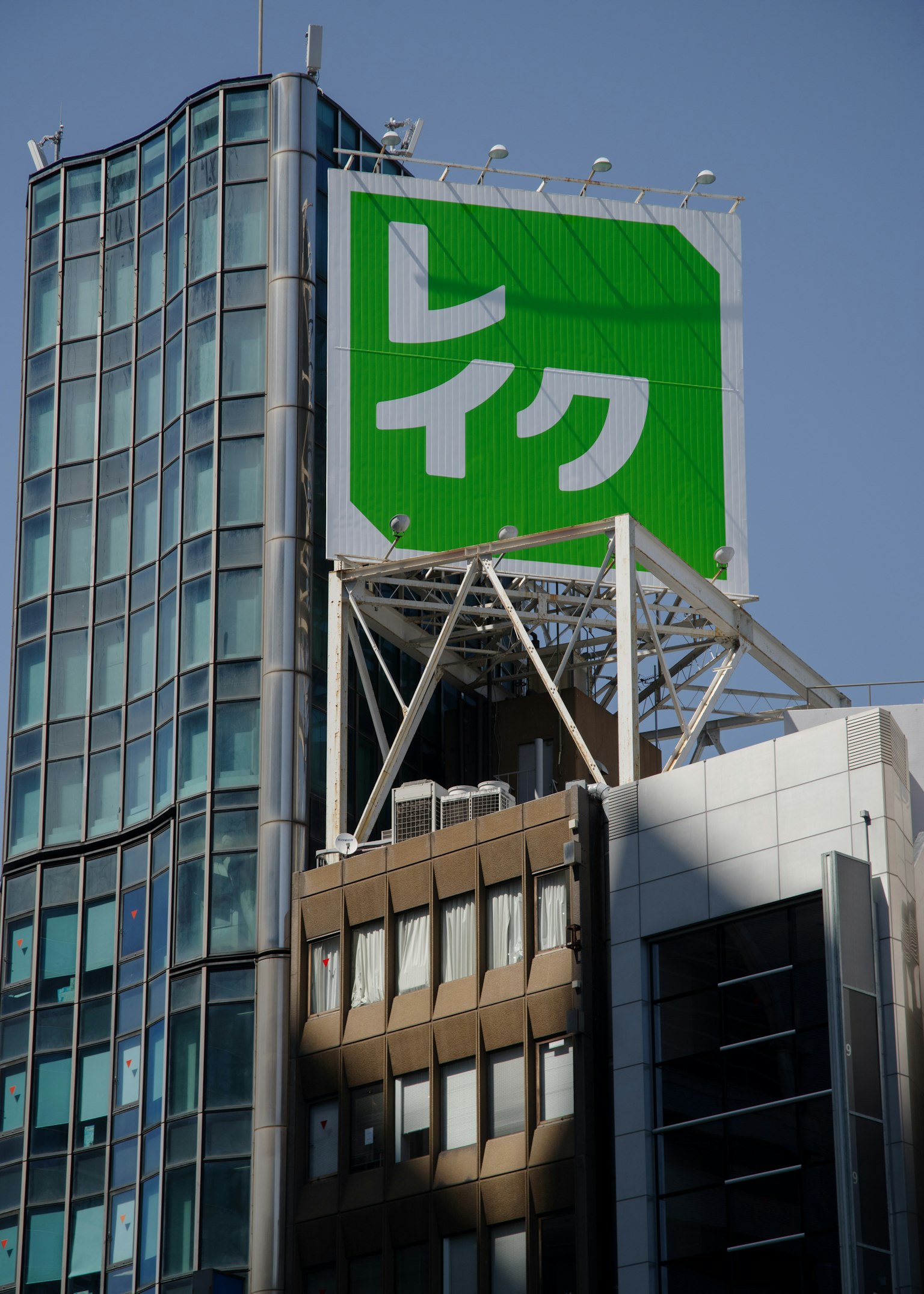 Un grand panneau vert avec le texte blanc 'レイク' sur le toit d'un bâtiment moderne