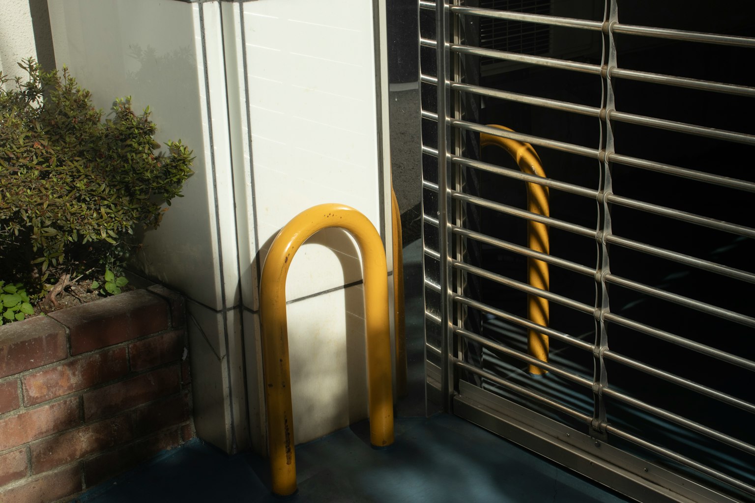 Yellow bike stand beside a shutter with reflection on the ground