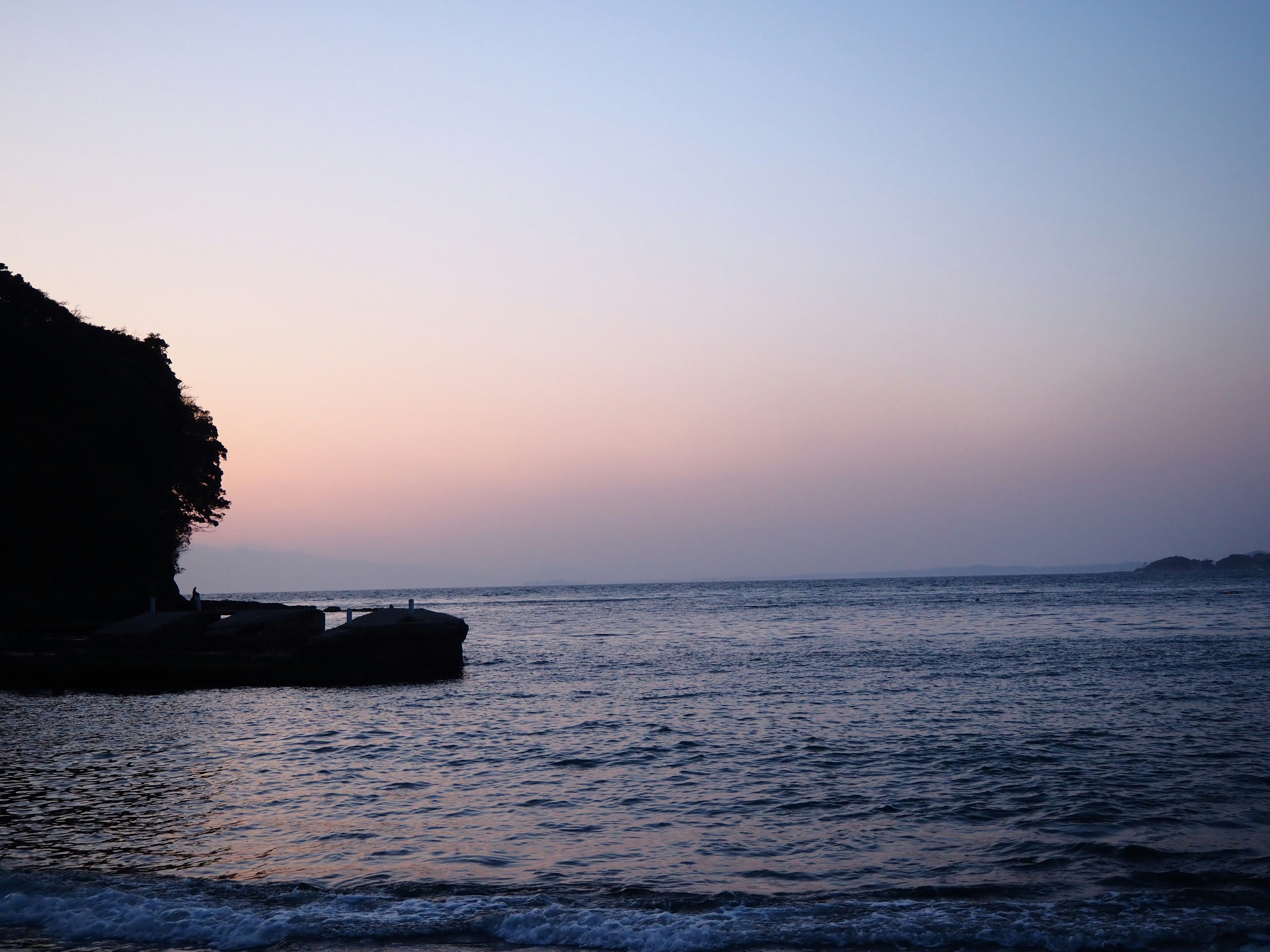 夕暮れの海辺と岩場のある小さな岬の風景