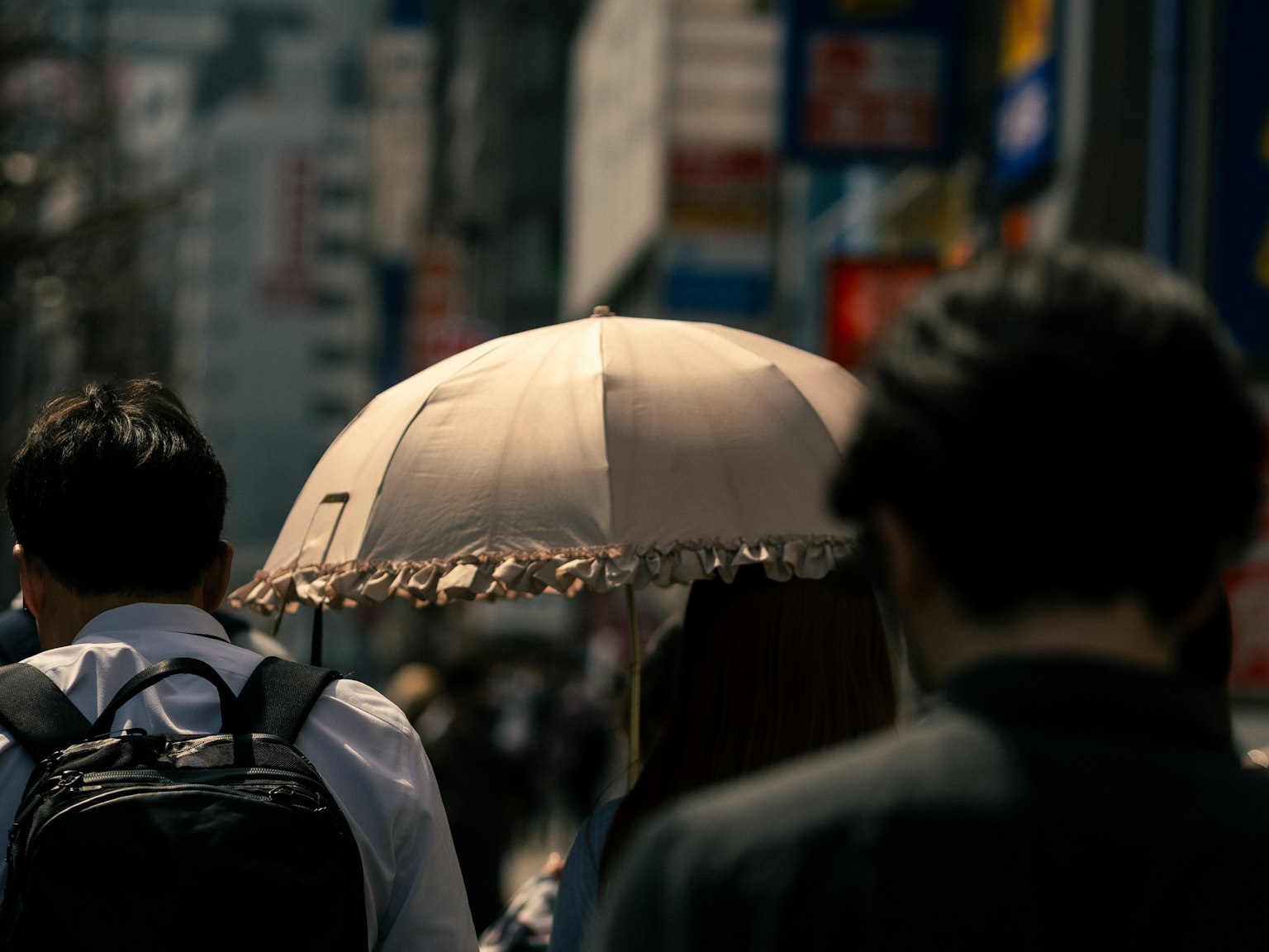 Mọi người đi bộ trên phố thành phố với một người phụ nữ cầm ô ở phía trước