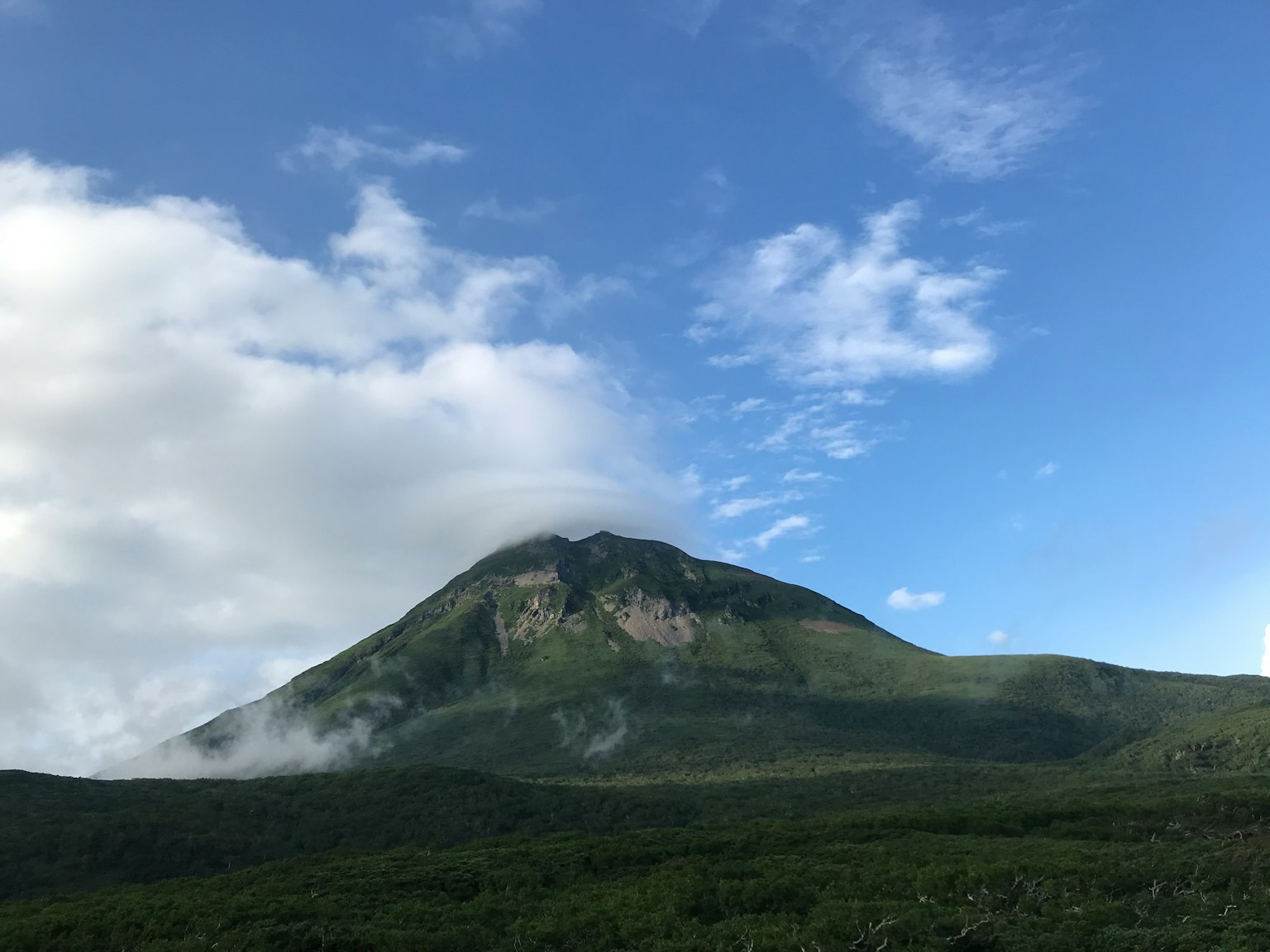 Una montagna verde sotto un cielo blu