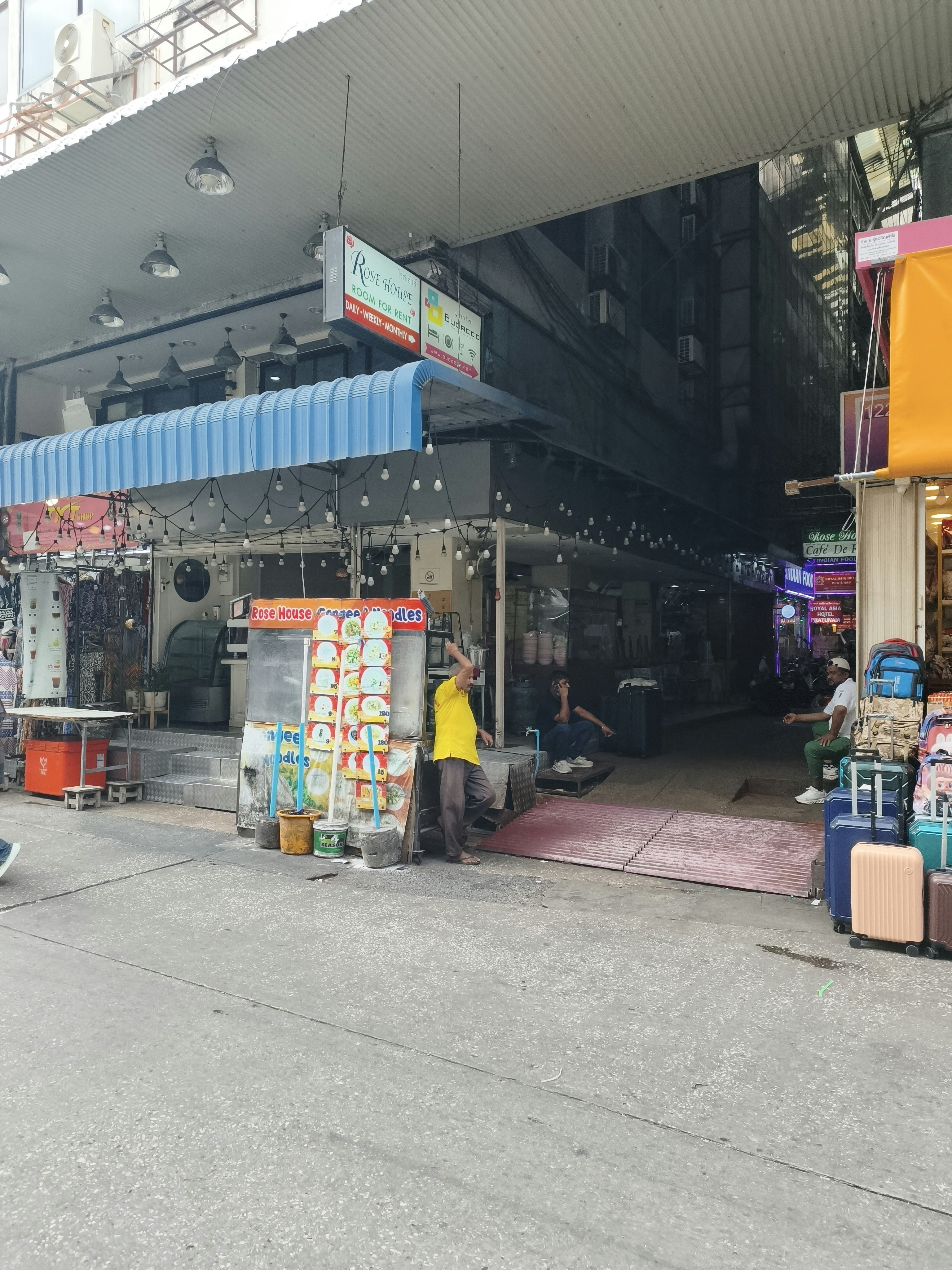 屋根付きの商店街通路で並ぶ自動販売機と旅行バッグ