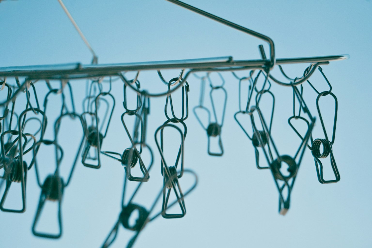 Close-up of clothespins hanging under a blue sky