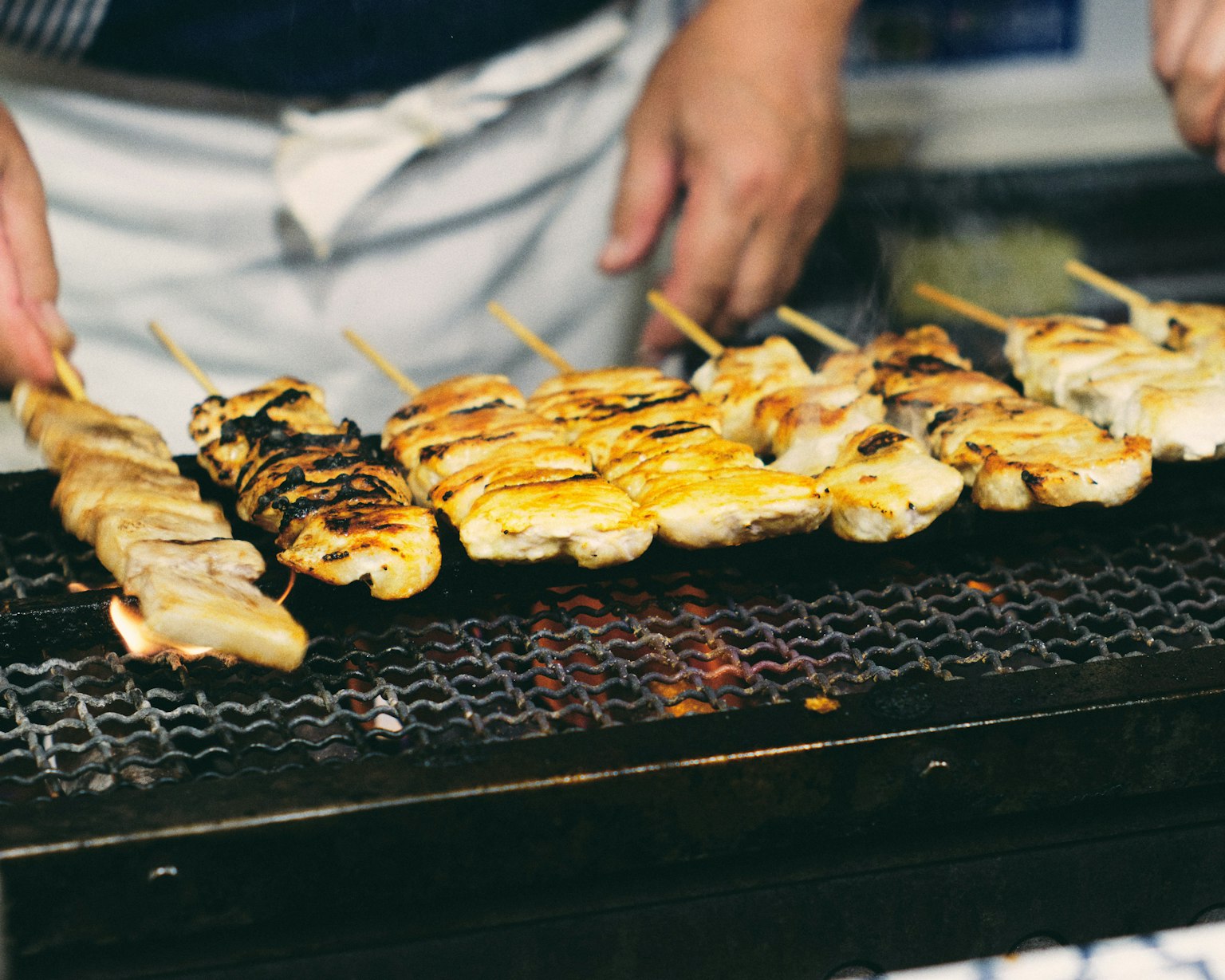 Spiedini di yakitori grigliati disposti su una griglia a carbone