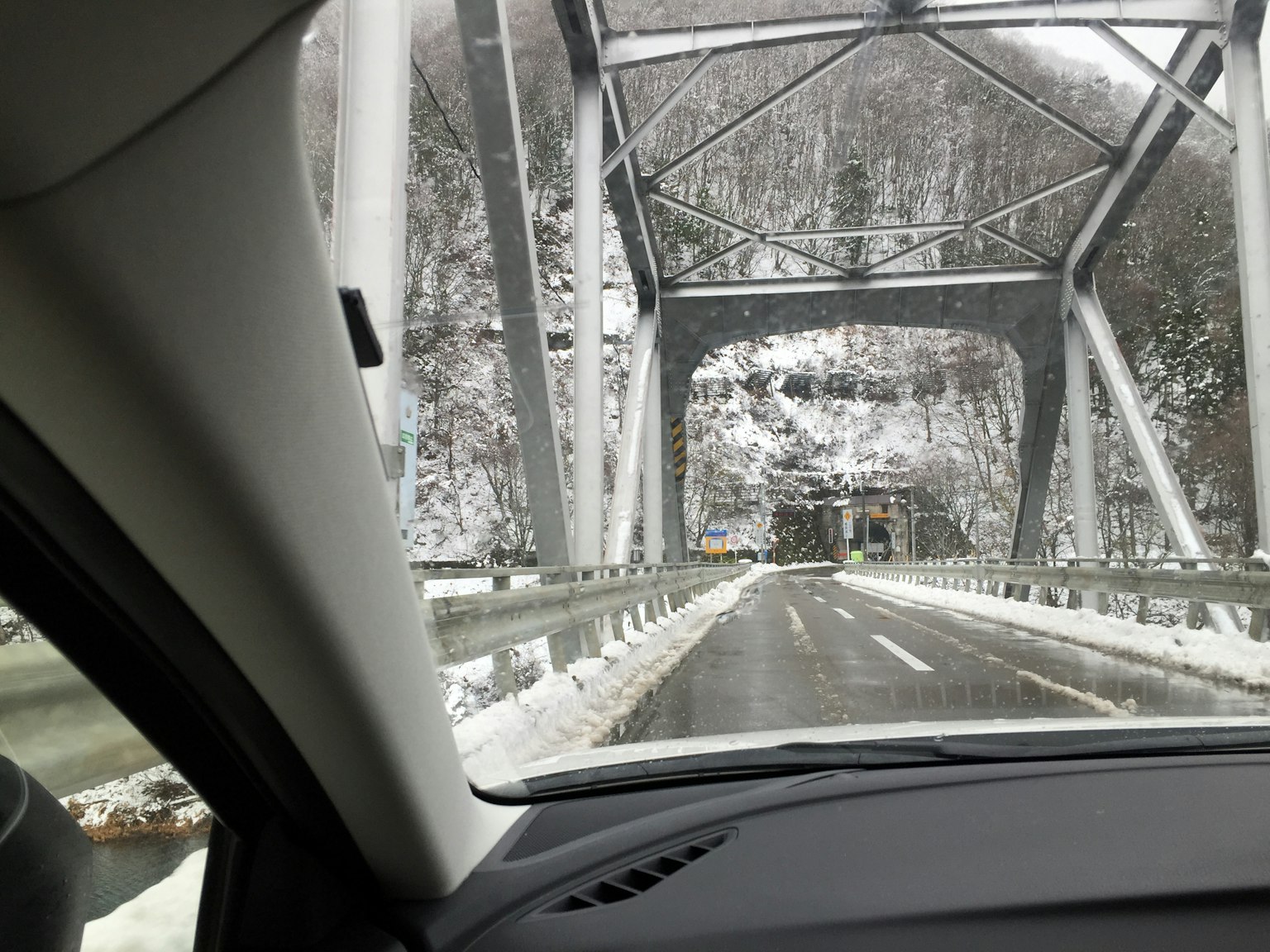 Vista interna di un'auto che attraversa un ponte coperto di neve