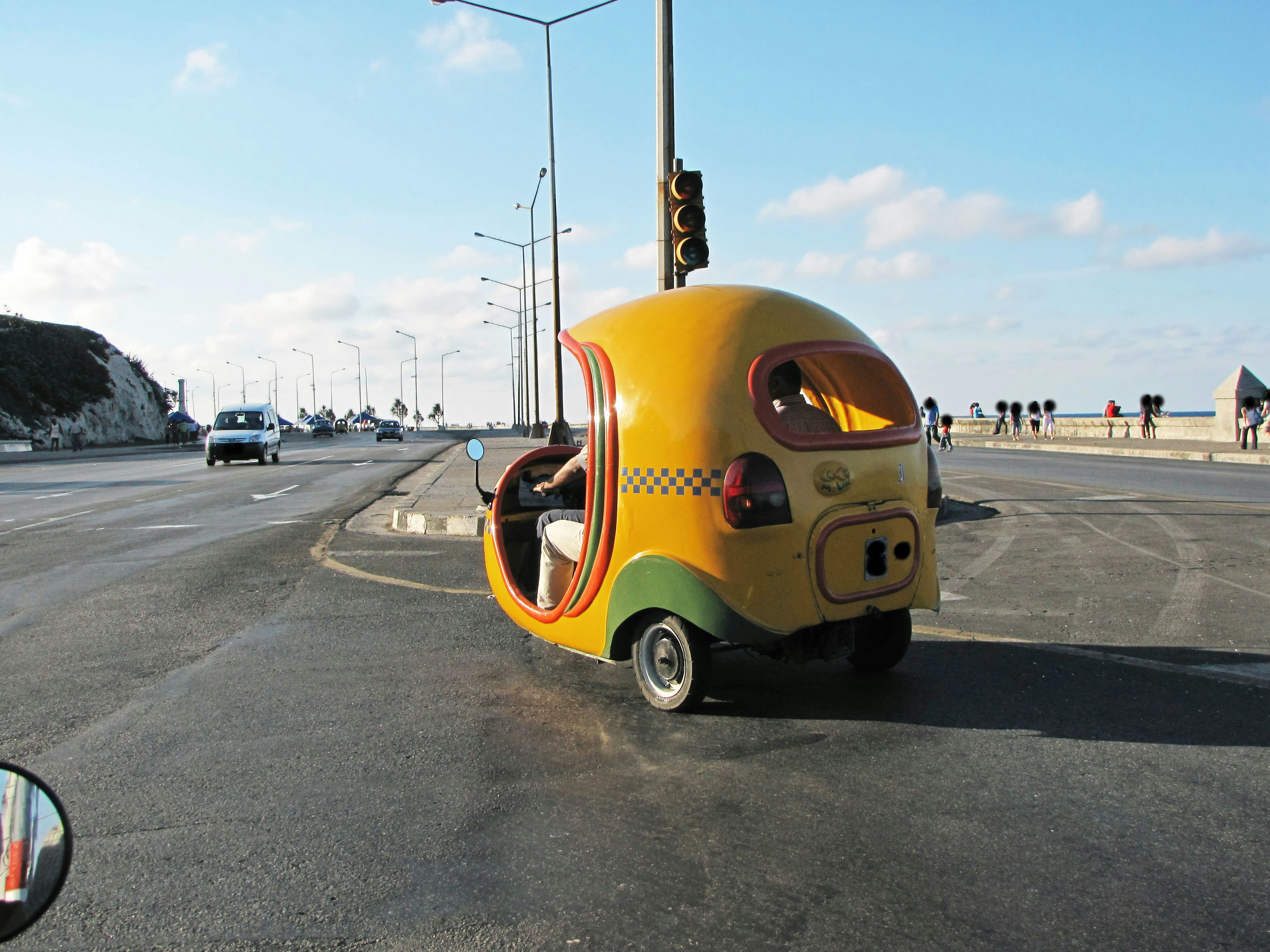 mini coche de tres ruedas colorido aparcado junto a la carretera