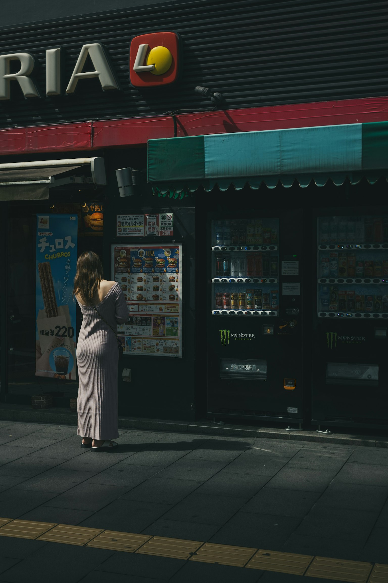一名女性站在自动售货机前，背景是商店