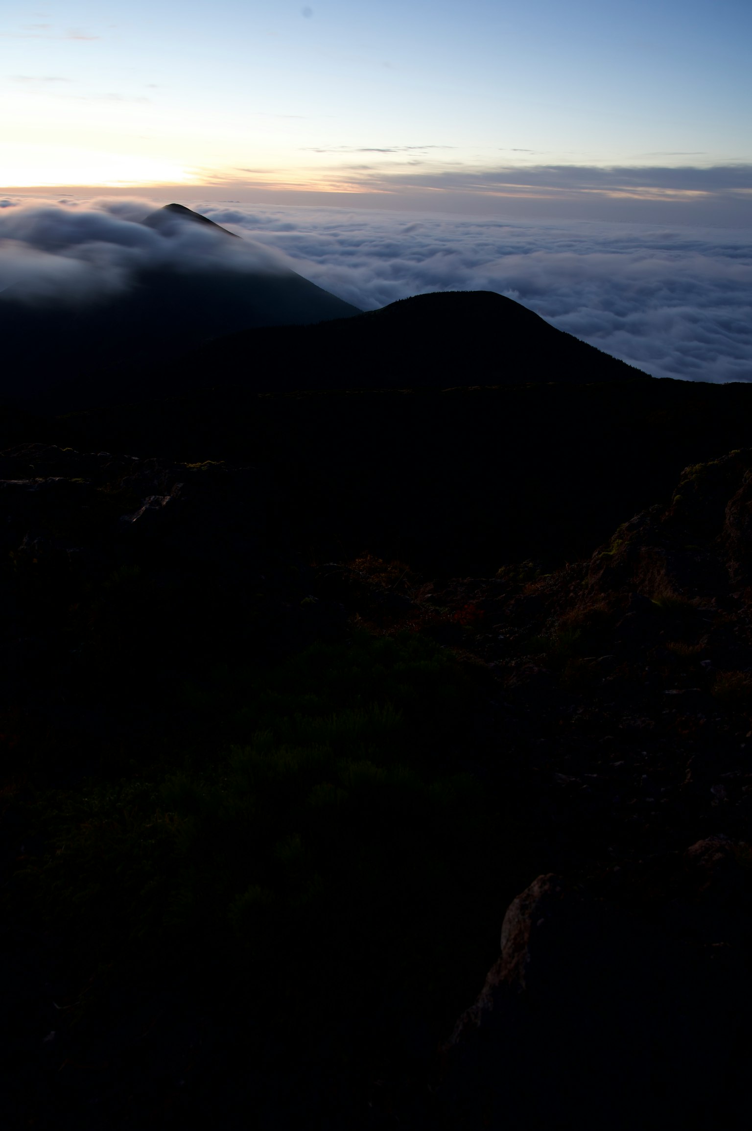 Silhouette of mountains above a sea of clouds with twilight sky