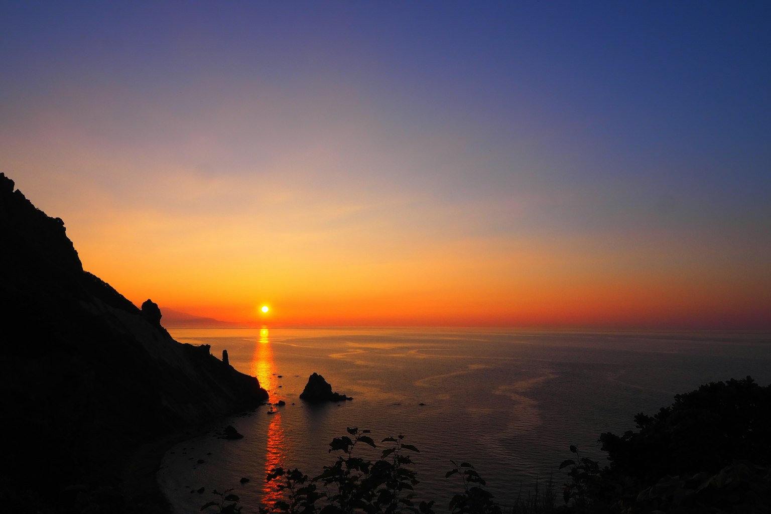 Stupendo tramonto sul mare con silhouette di rocce