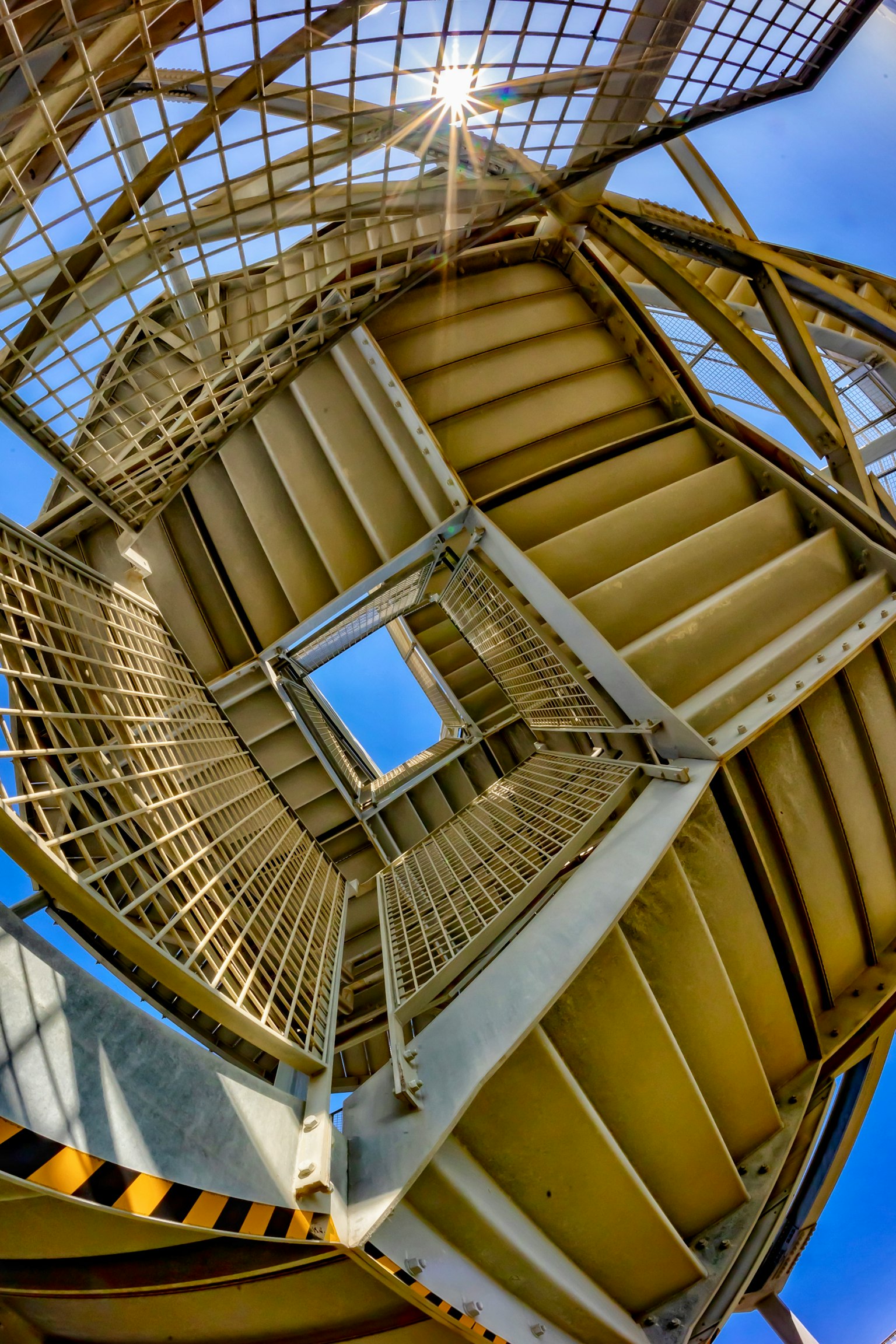 Blick auf eine Wendeltreppe von unten mit einem Blick auf den blauen Himmel