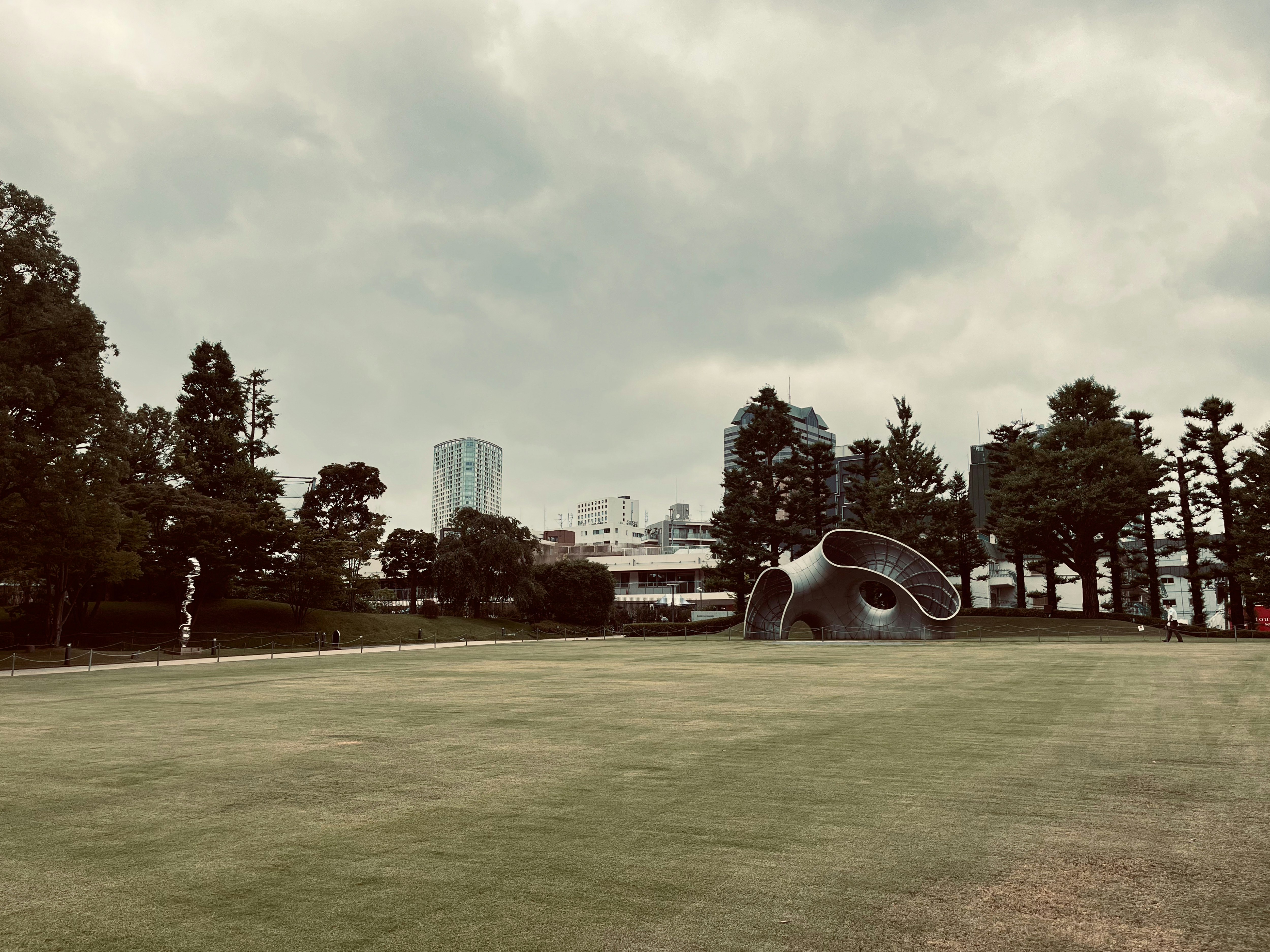 grassy plaza with a white monument under an overcast sky