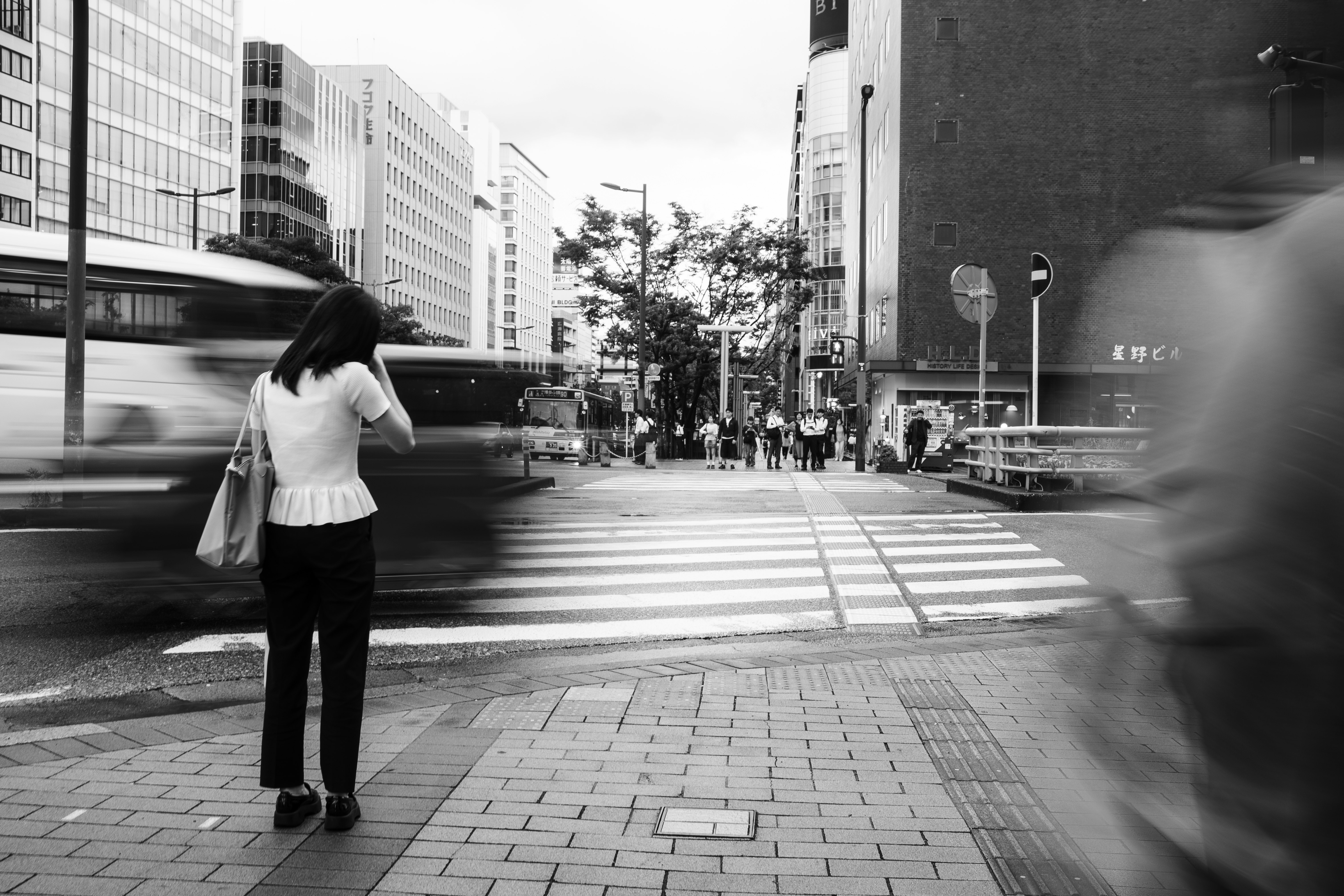 Cruce urbano en blanco y negro con una persona sosteniendo bolsas de compras